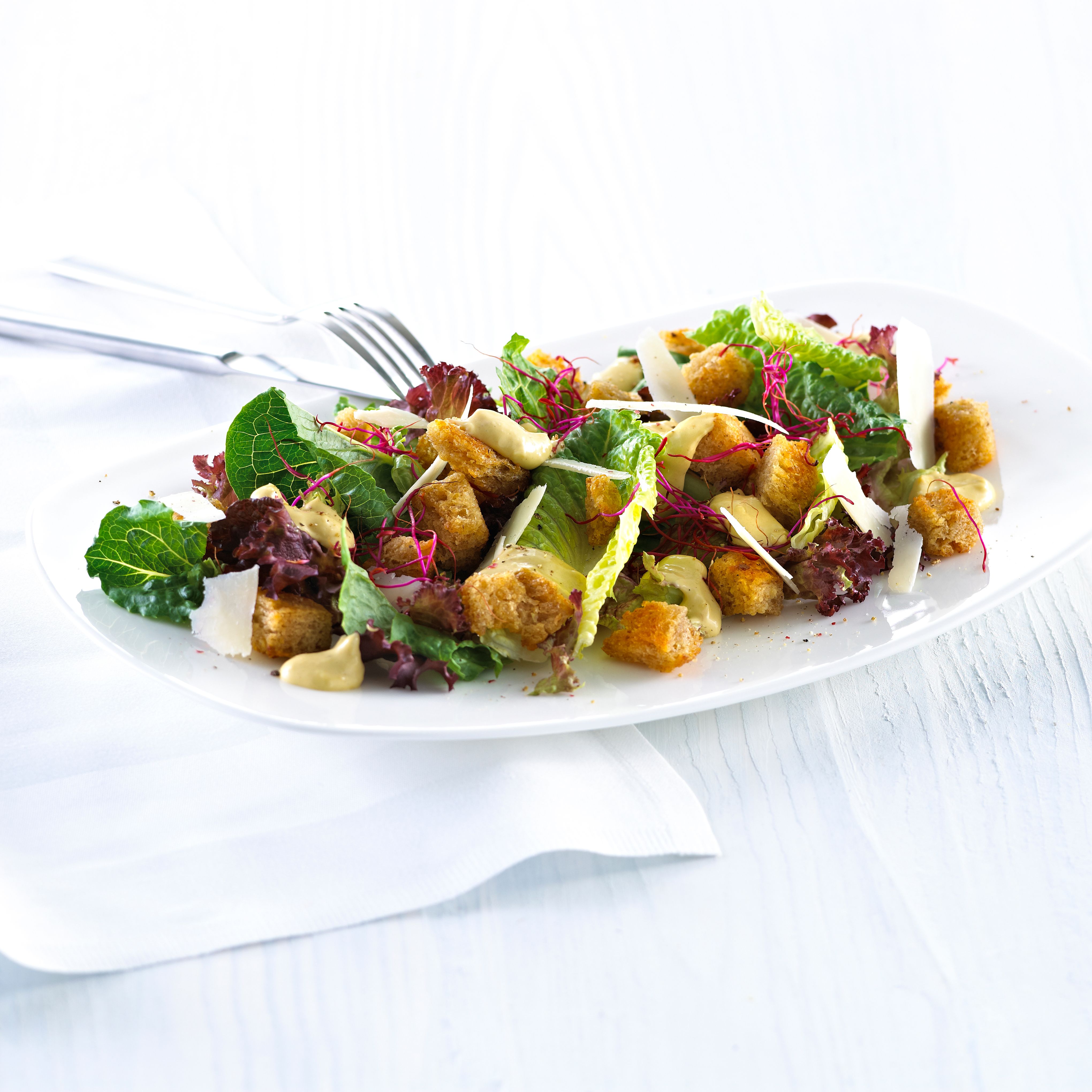 Blandet salat med krutonger og skivet parmesan.