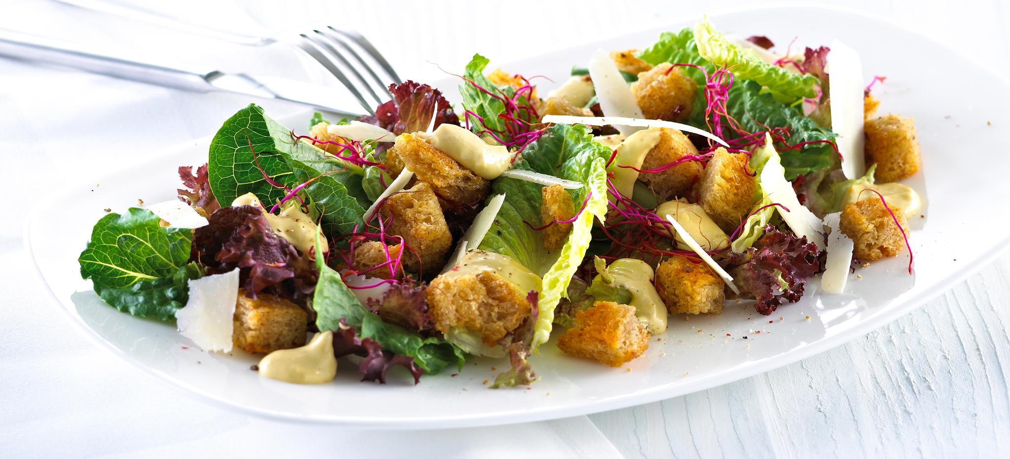 Blandet salat med krutonger og skivet parmesan.