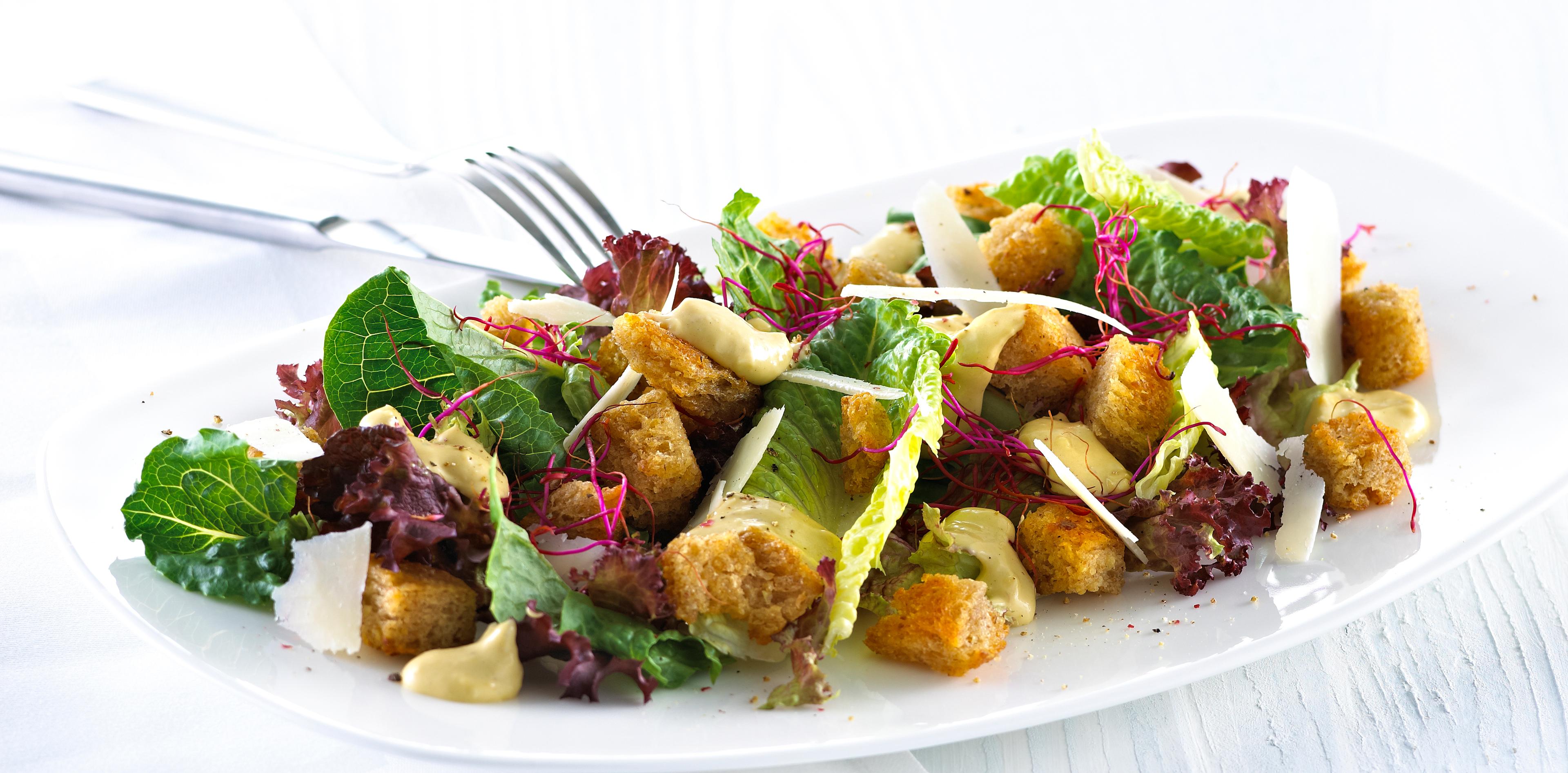 Blandet salat med krutonger og skivet parmesan.