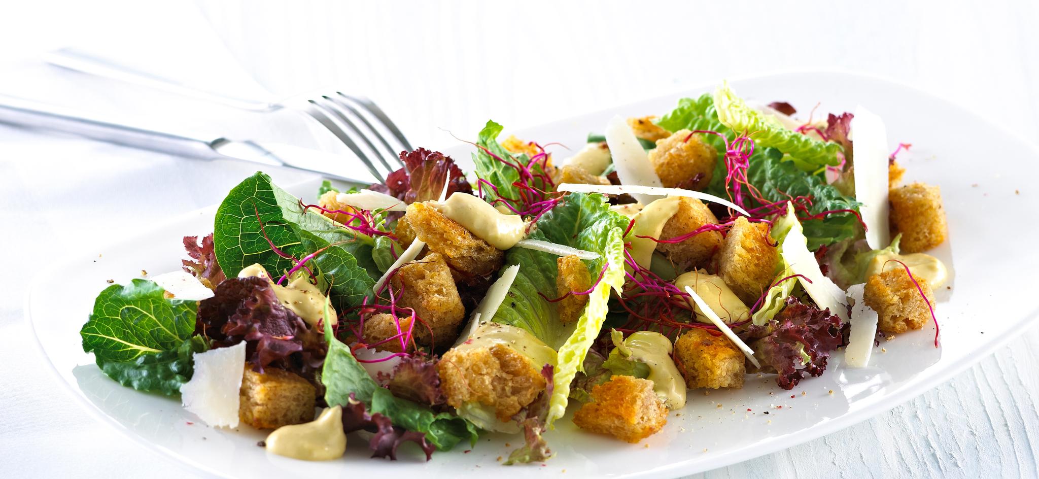 Blandet salat med krutonger og skivet parmesan.