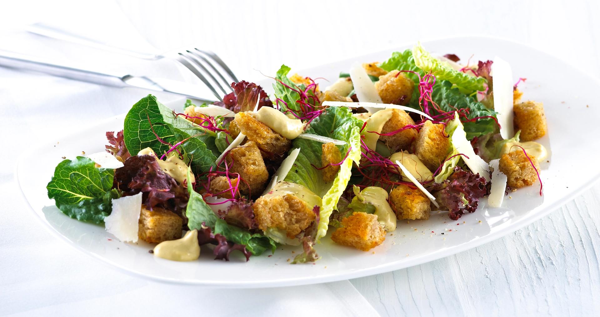 Blandet salat med krutonger og skivet parmesan.