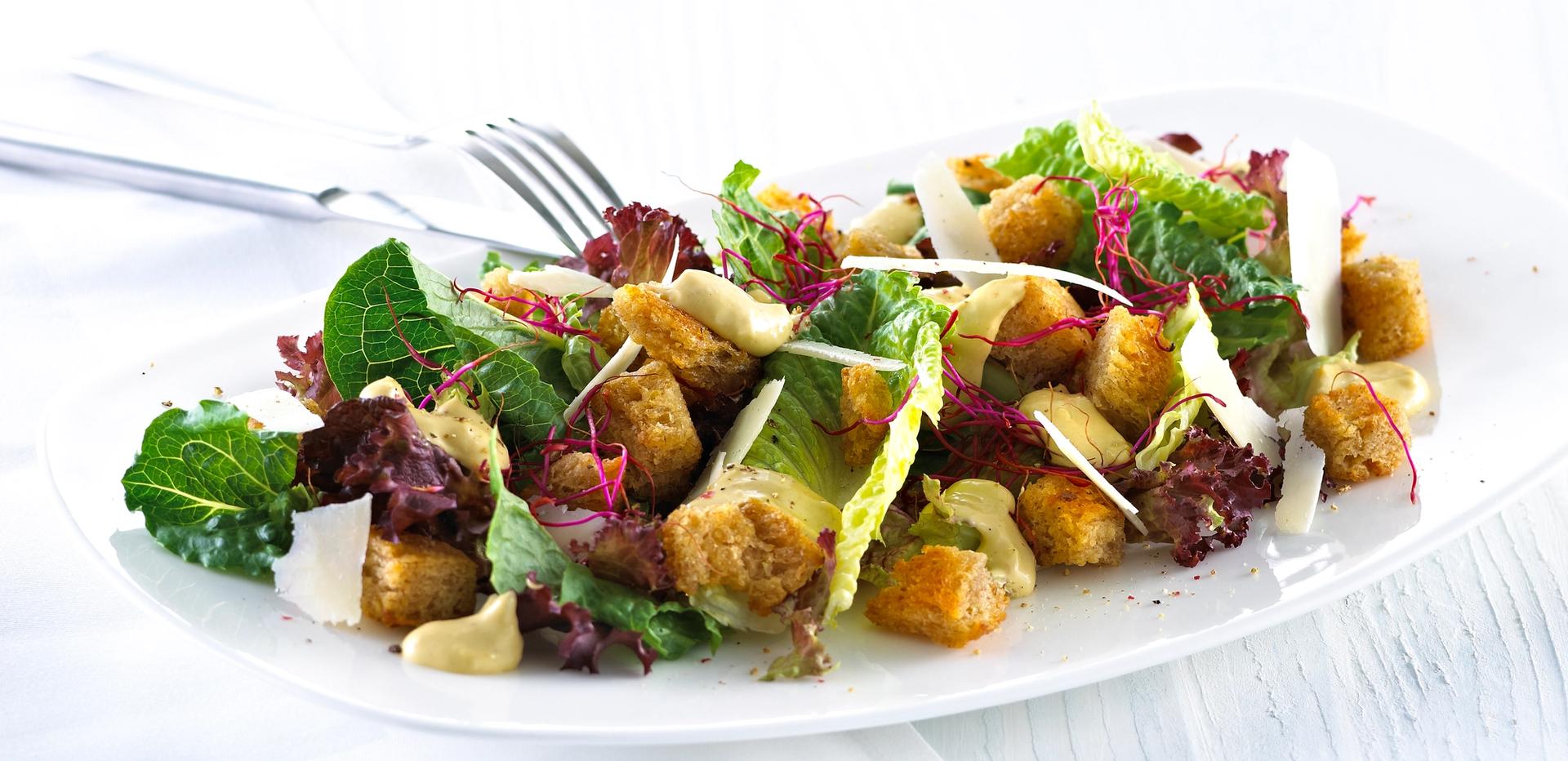 Blandet salat med krutonger og skivet parmesan.