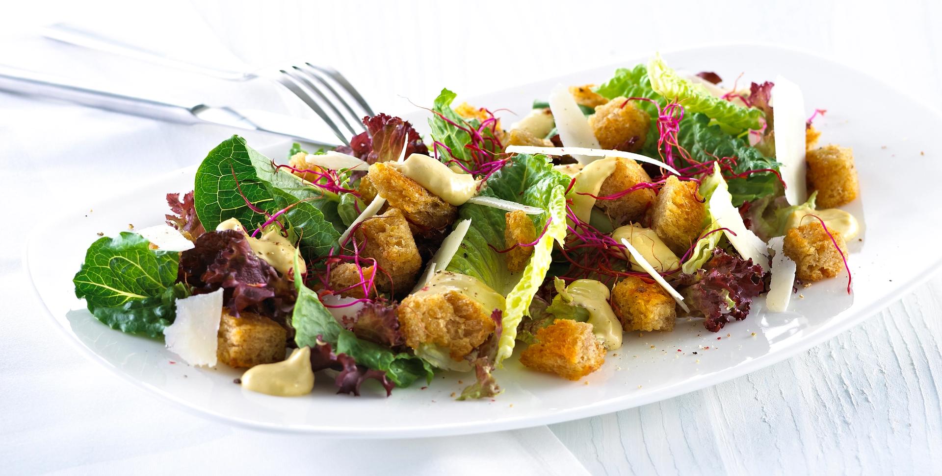 Blandet salat med krutonger og skivet parmesan.