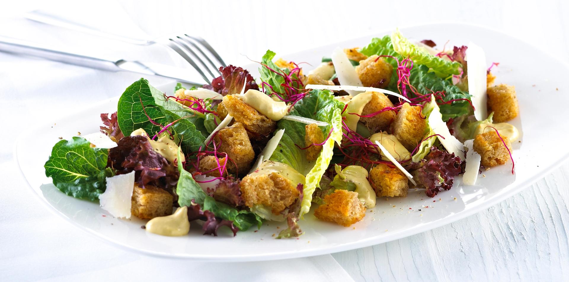 Blandet salat med krutonger og skivet parmesan.