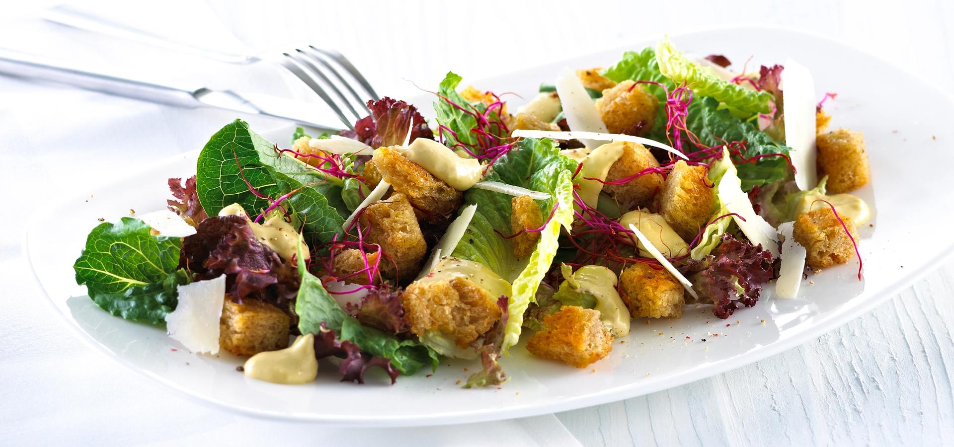 Blandet salat med krutonger og skivet parmesan.