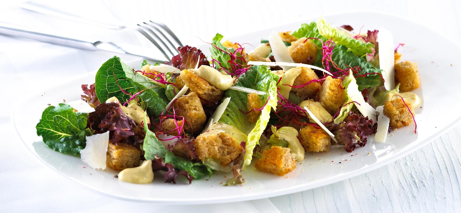 Blandet salat med krutonger og skivet parmesan.