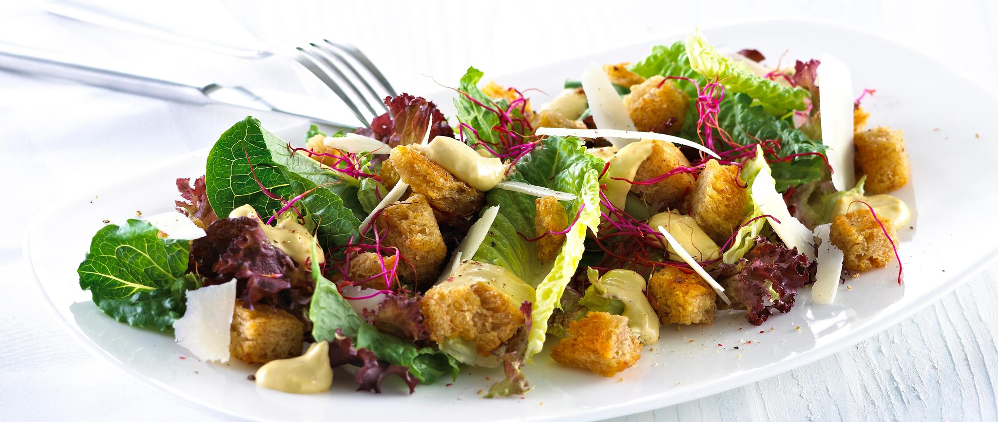Blandet salat med krutonger og skivet parmesan.