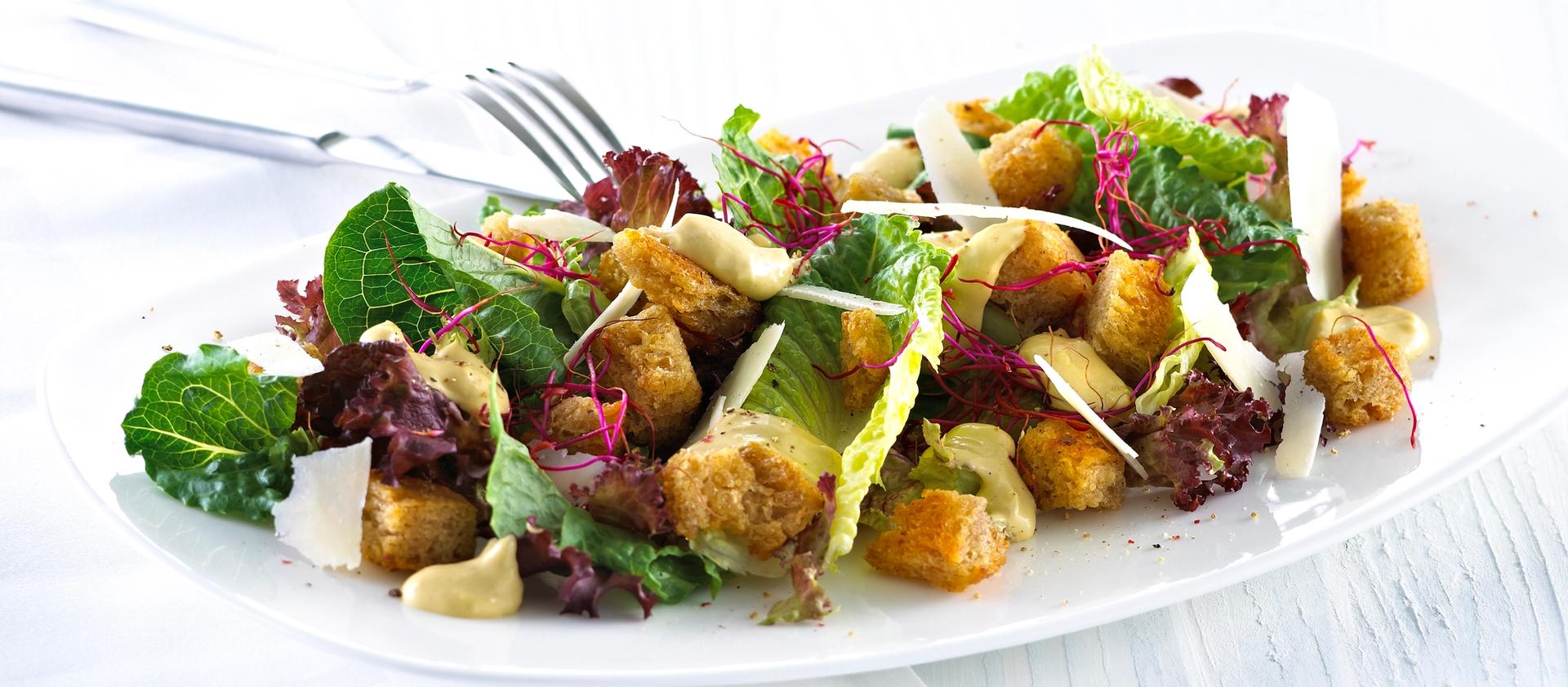 Blandet salat med krutonger og skivet parmesan.