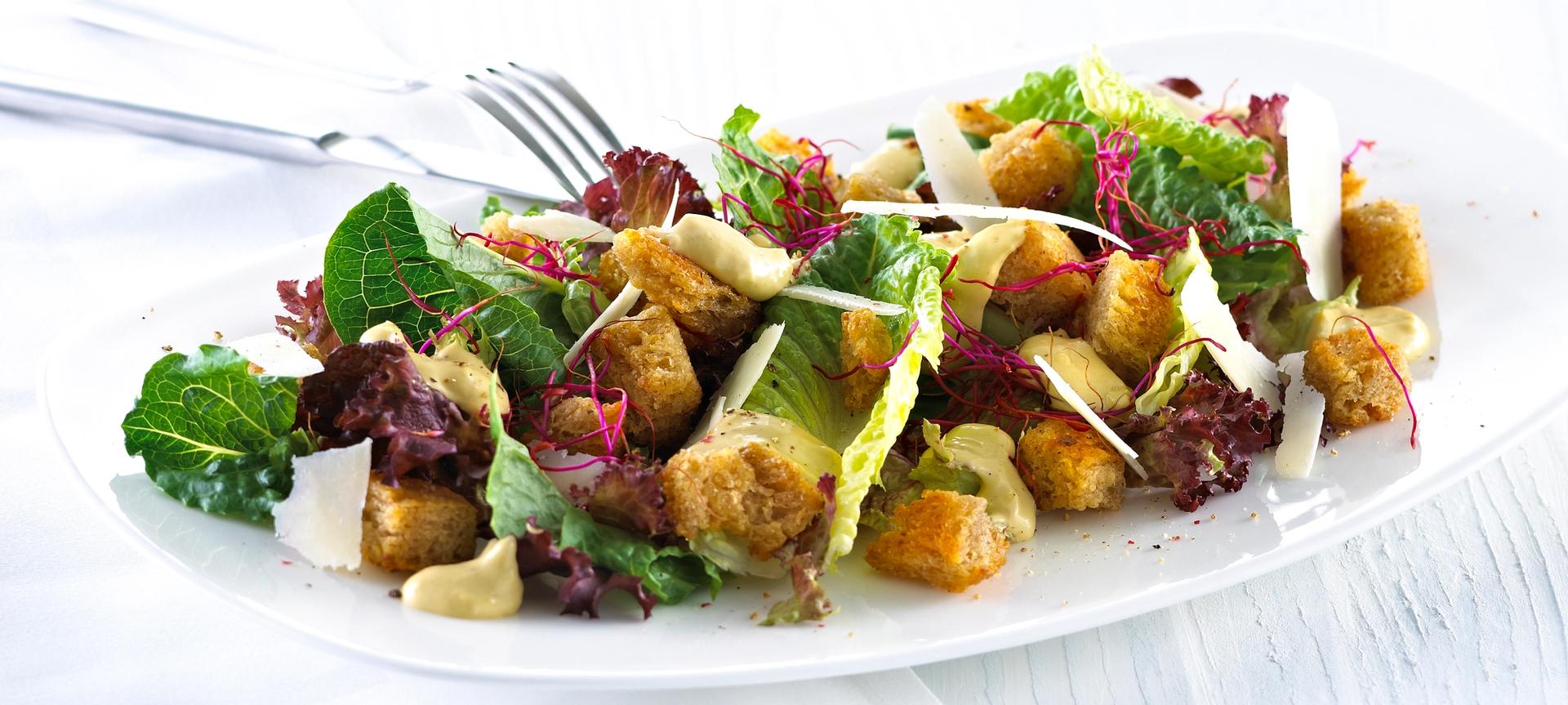 Blandet salat med krutonger og skivet parmesan.