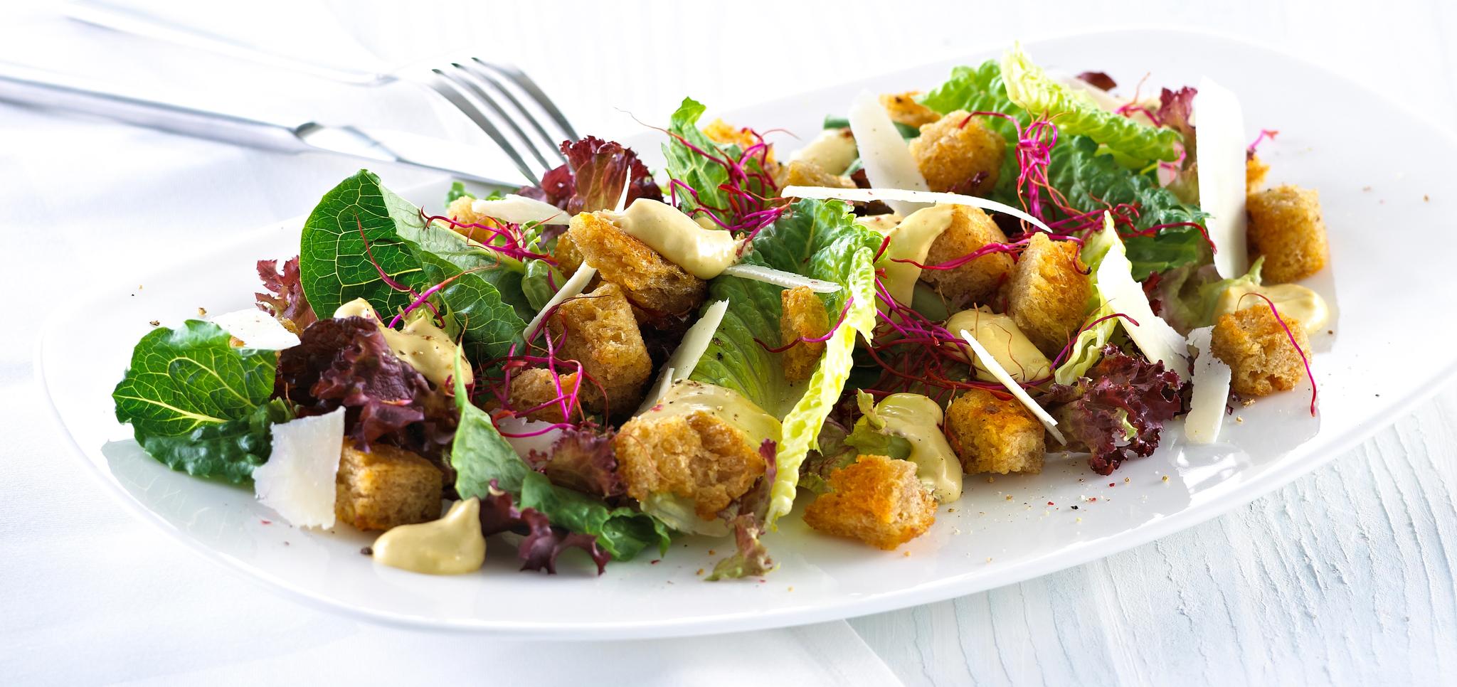 Blandet salat med krutonger og skivet parmesan.