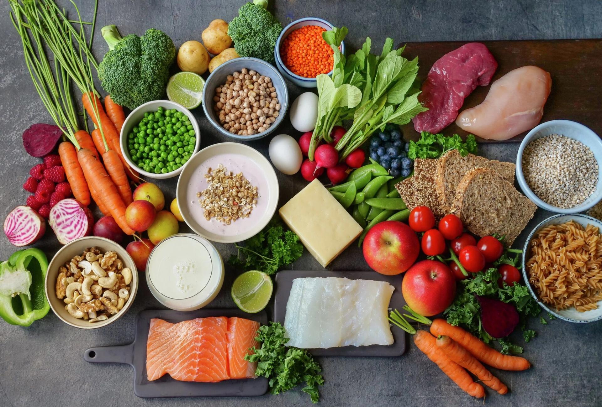 A diverse spread of colorful, healthy foods including fresh fruits, vegetables, proteins, grains, and dairy.