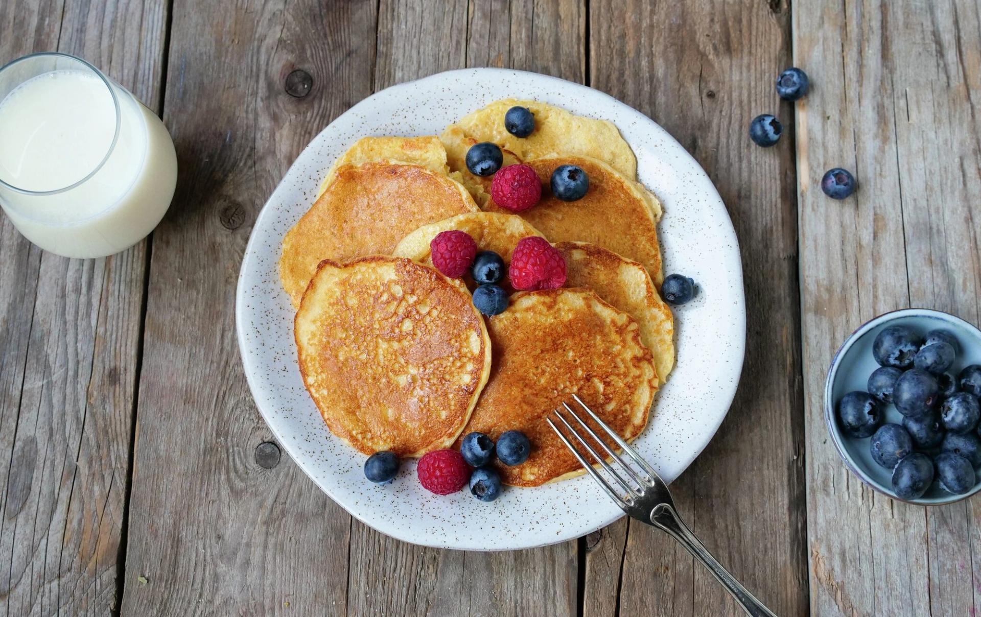 Tallerken med små pannekaker med blåbær og bringebær