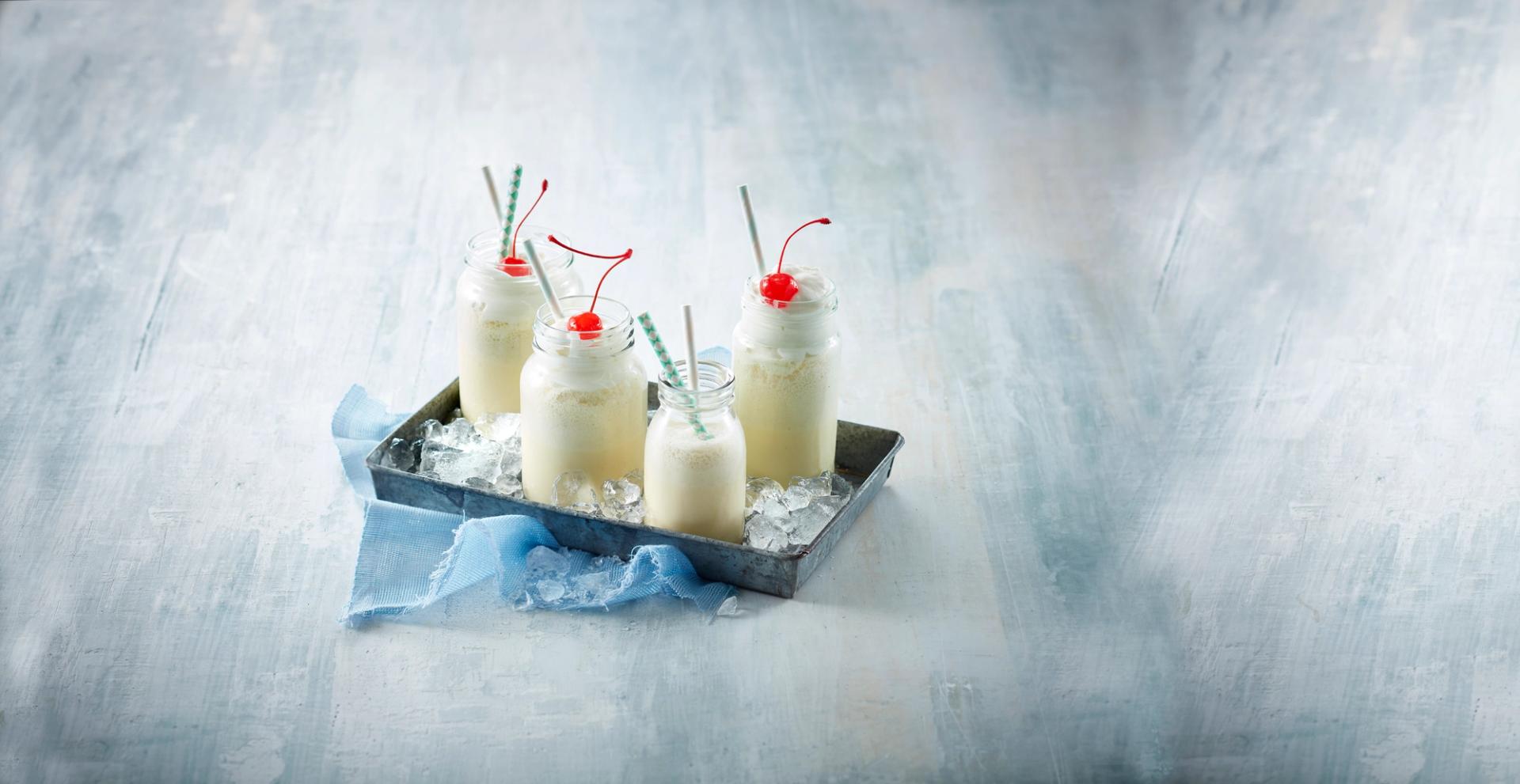 Vaniljeshake i flasker med krem og kirsebær på toppen 