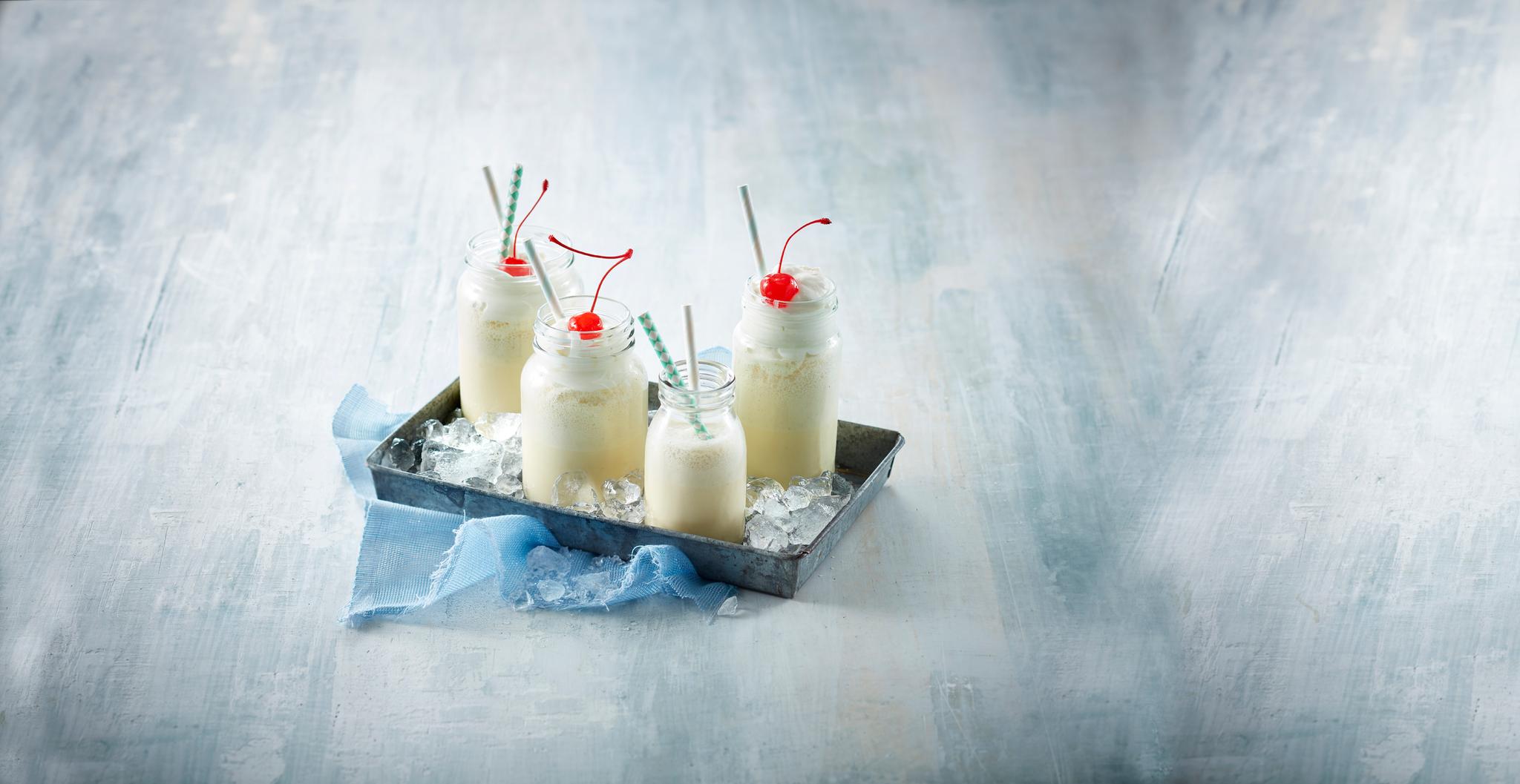 Vaniljeshake i flasker med krem og kirsebær på toppen 