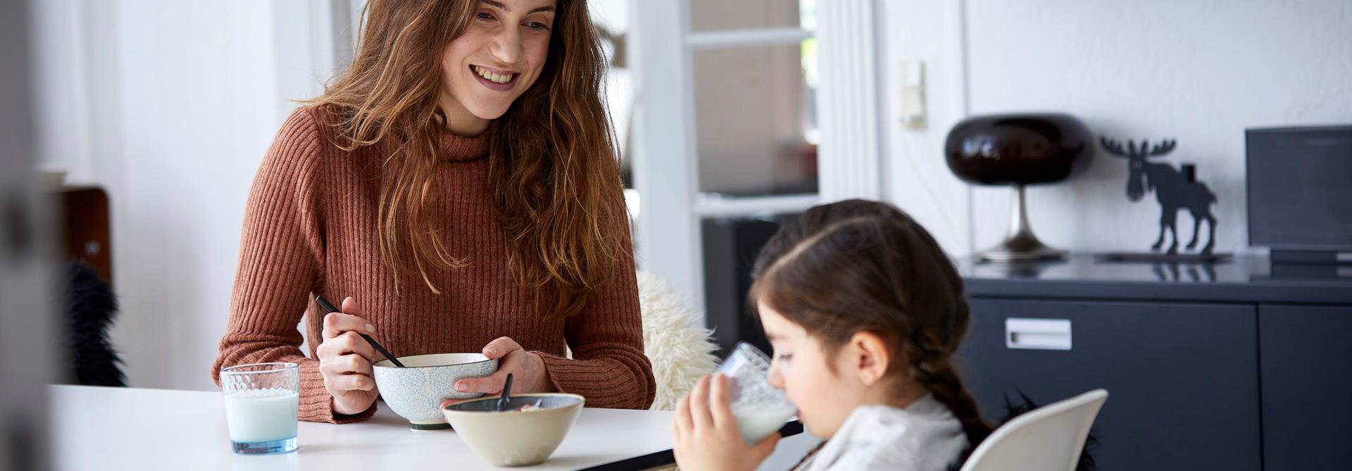 Mor med musliskål og datter med melkeglass