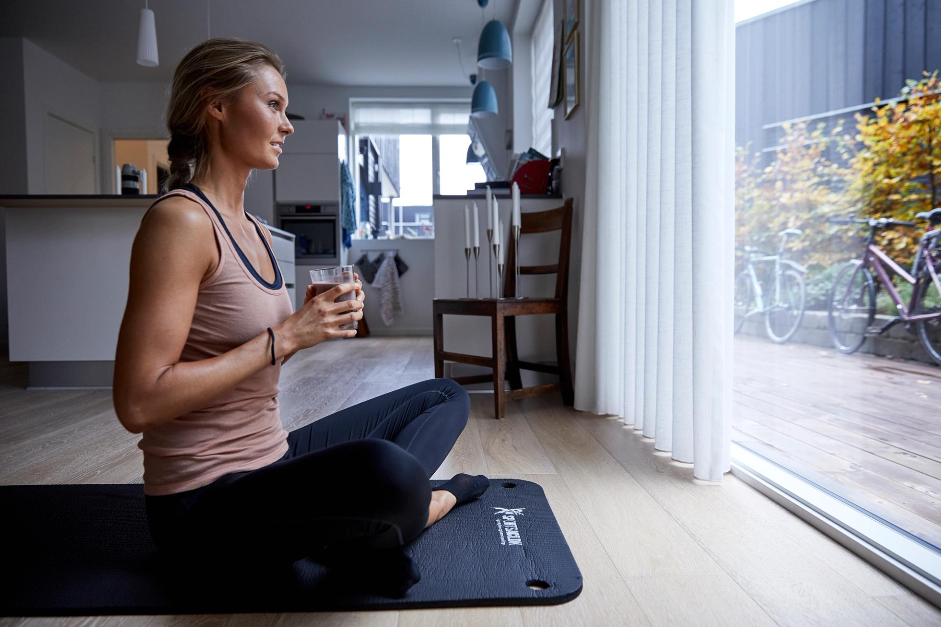 Kvinne som sitter på treningsmatte