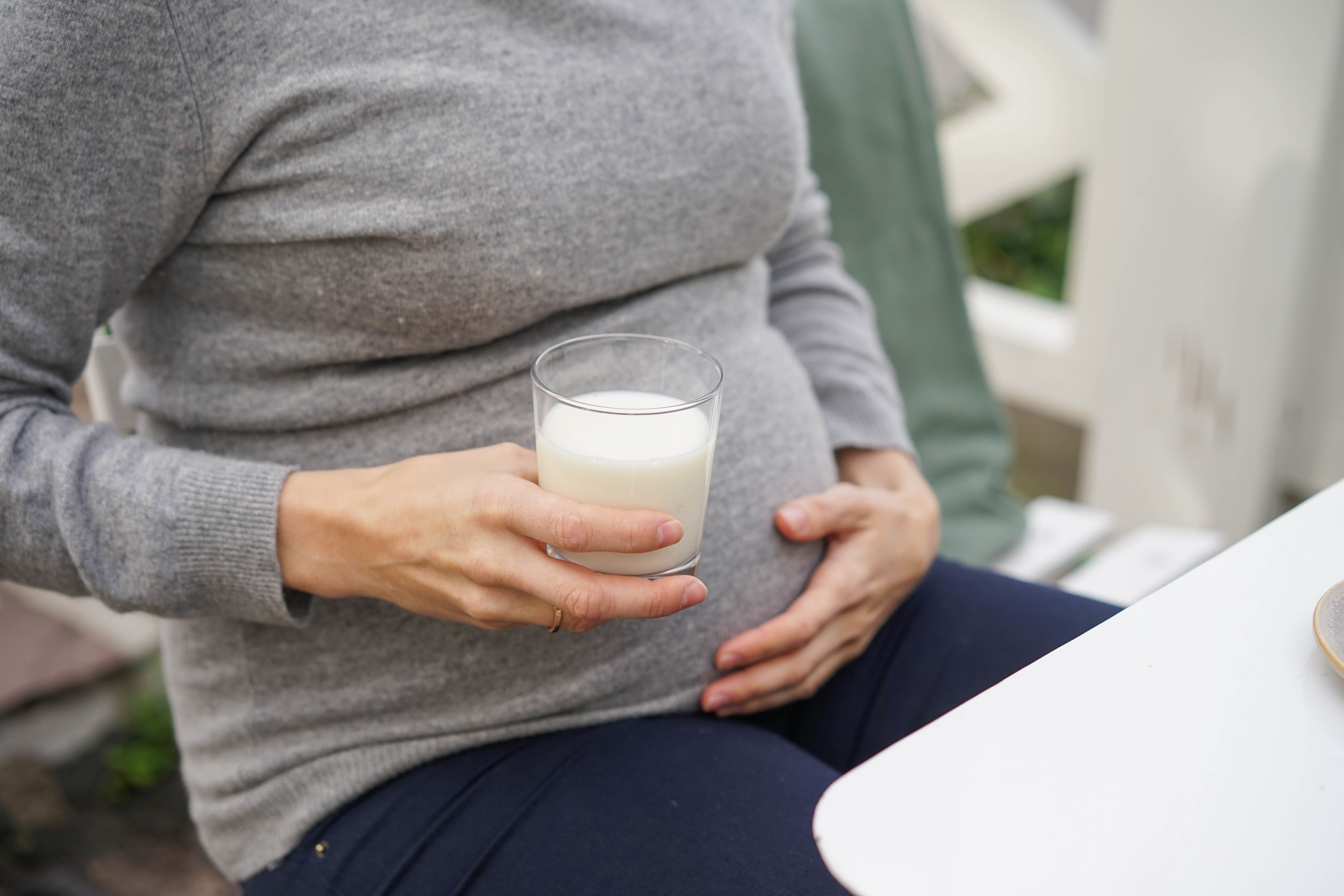 gravid kvinne holder et glass melk