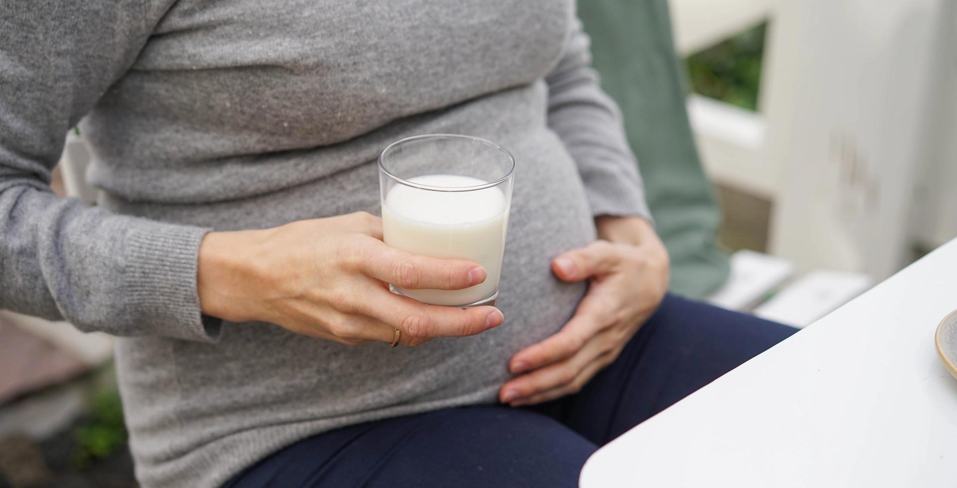 gravid kvinne holder et glass melk