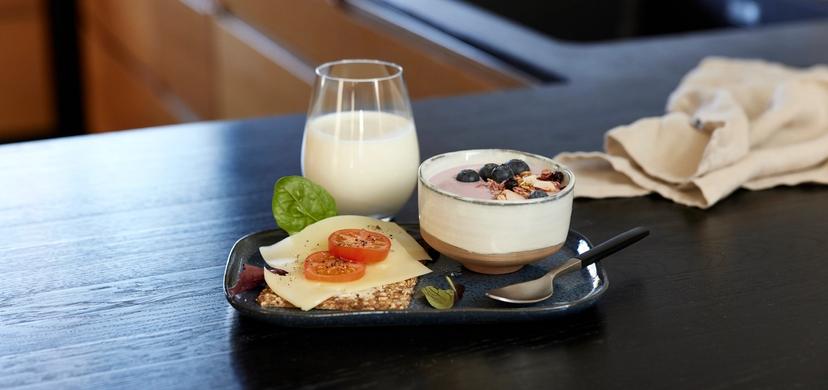 Knekkebrød med gulost og reddik, et glass melk og en skål yoghurt med bær