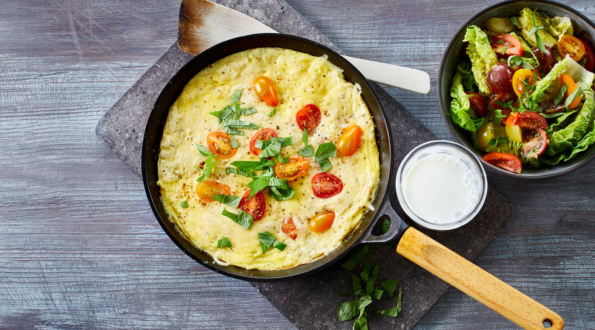 Omelett med tomat, ost og basilikum, med et glass melk og salat til