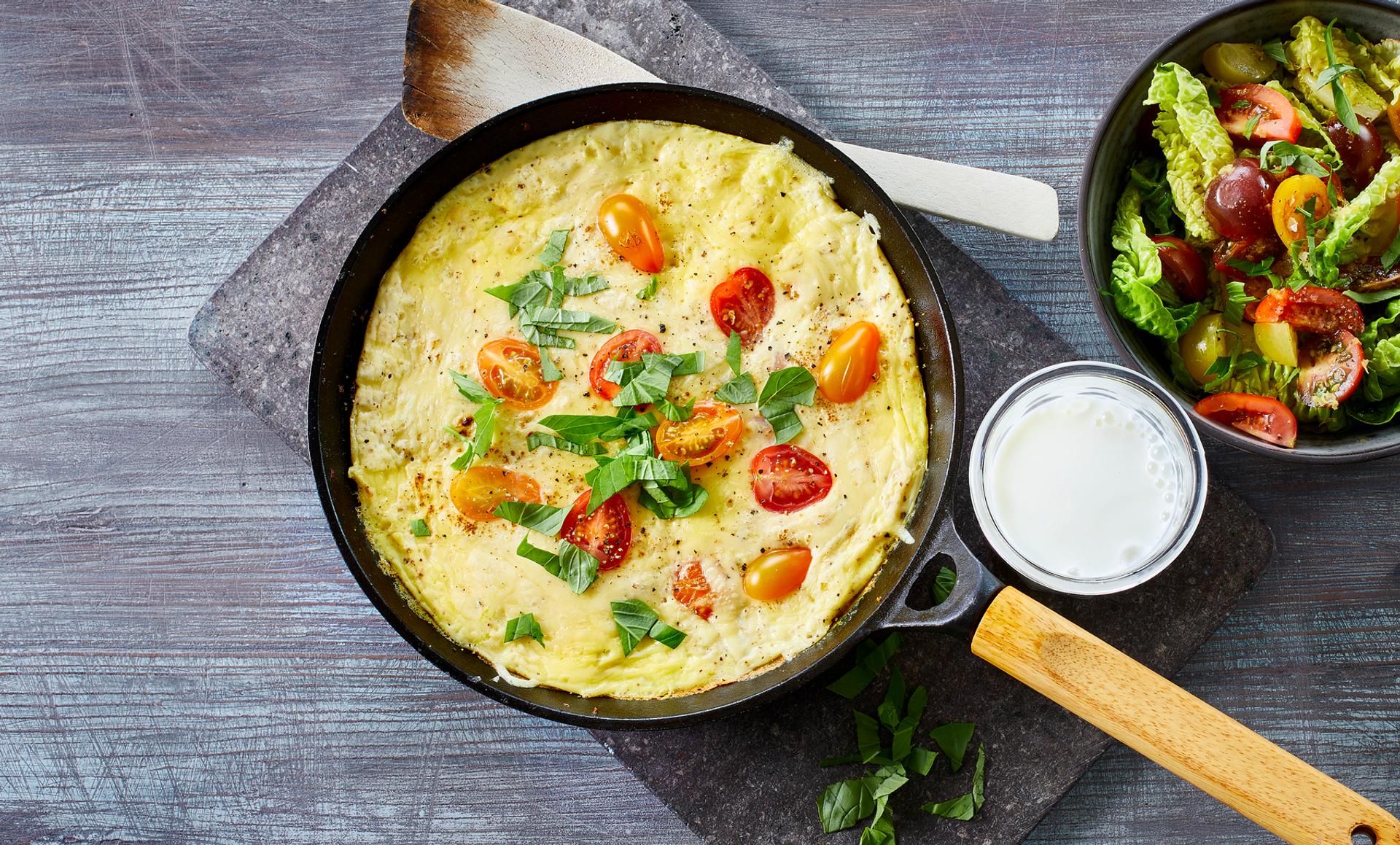 Omelett med tomat, ost og basilikum, med et glass melk og salat til