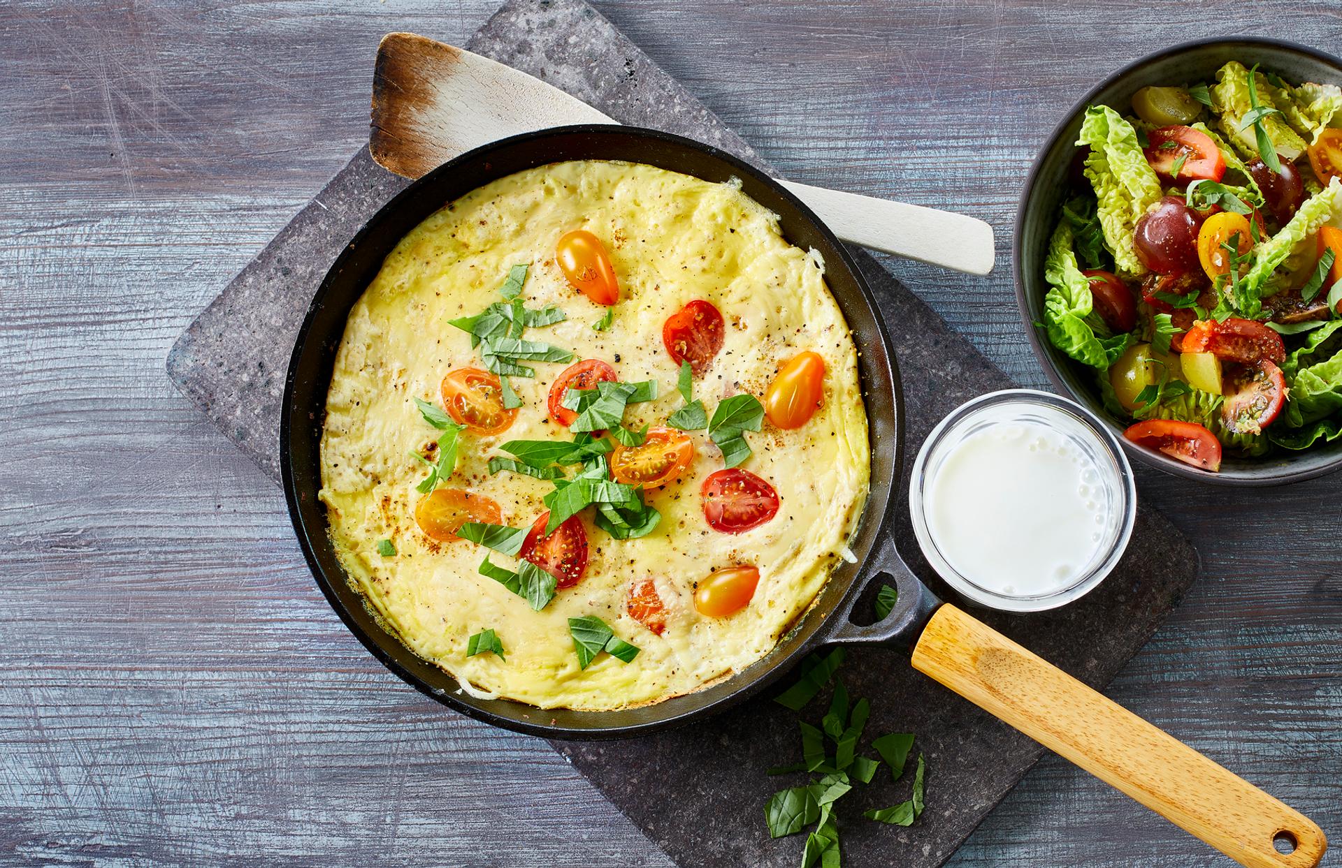 Omelett med tomat, ost og basilikum, med et glass melk og salat til