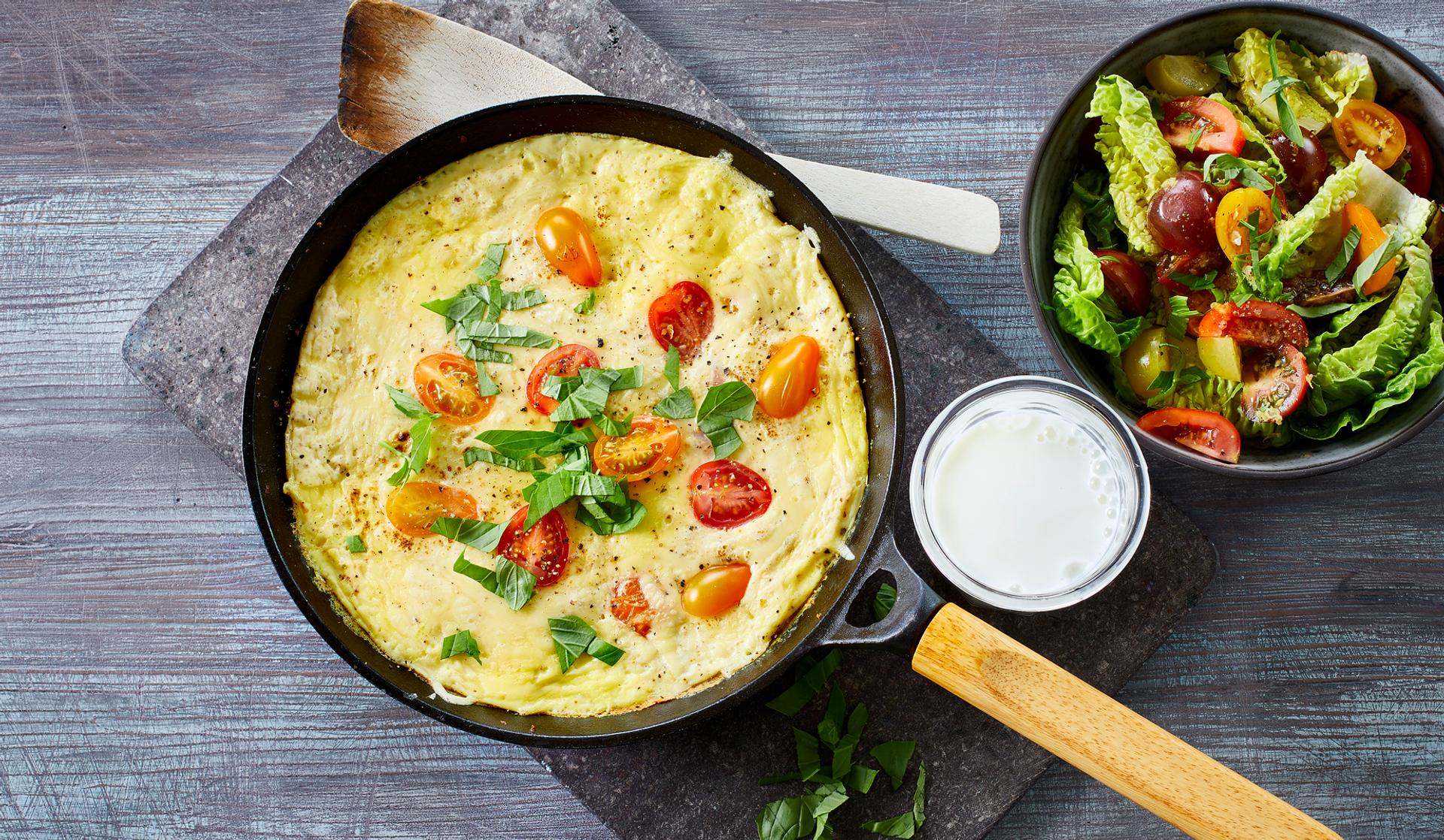 Omelett med tomat, ost og basilikum, med et glass melk og salat til