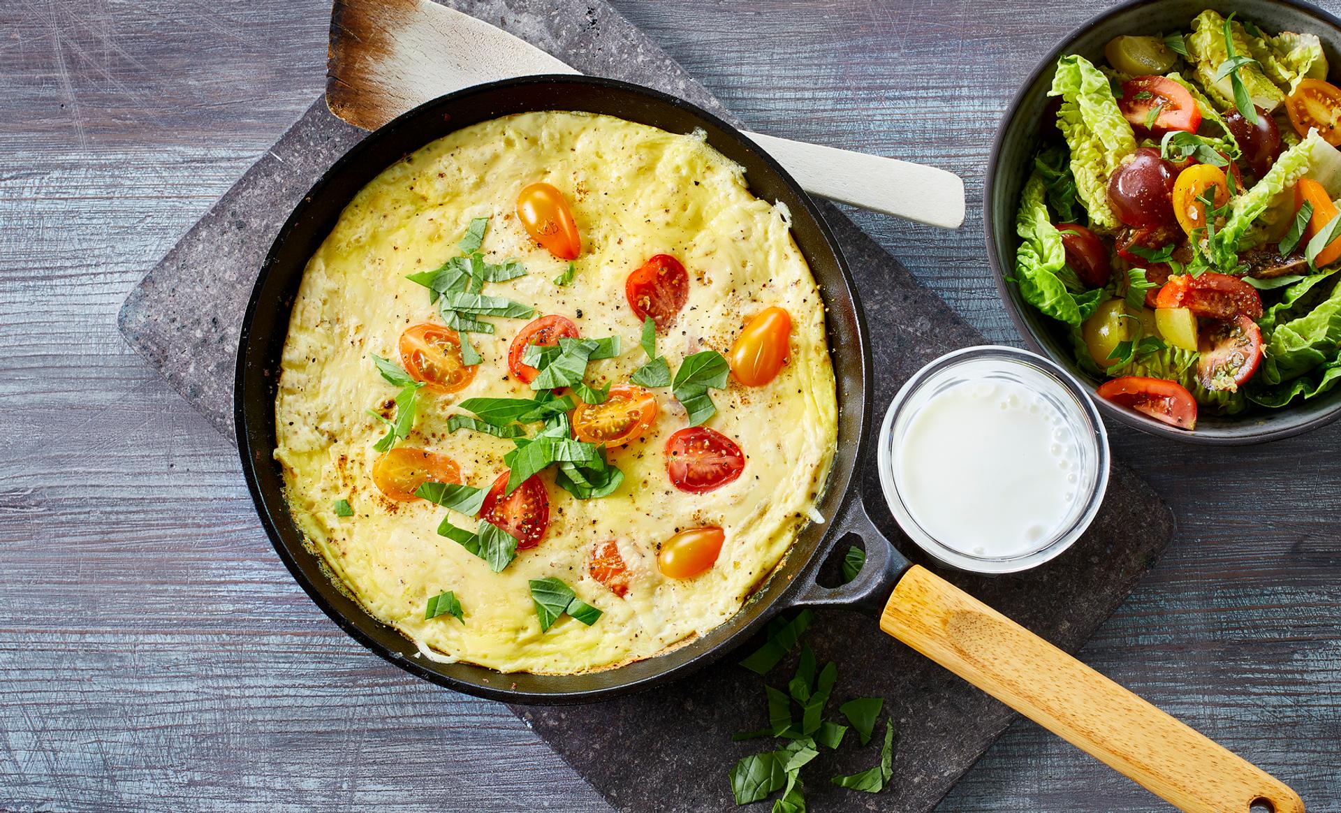 Omelett med tomat, ost og basilikum, med et glass melk og salat til