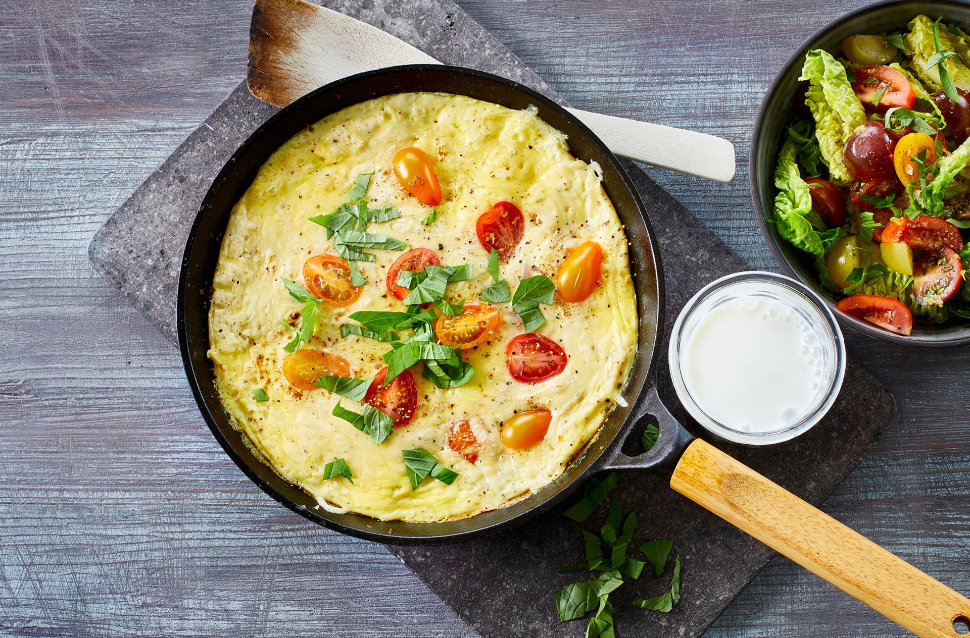 Omelett med tomat, ost og basilikum, med et glass melk og salat til