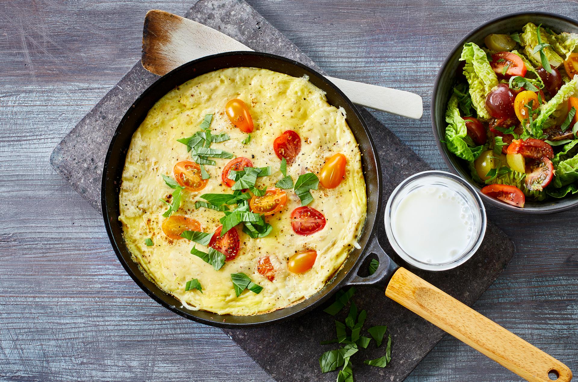 Omelett med tomat, ost og basilikum, med et glass melk og salat til
