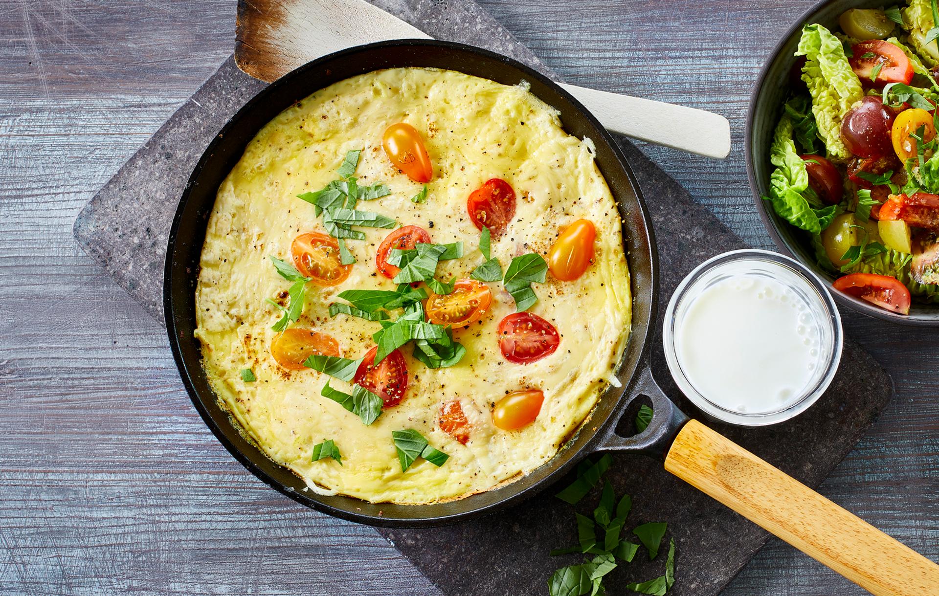 Omelett med tomat, ost og basilikum, med et glass melk og salat til