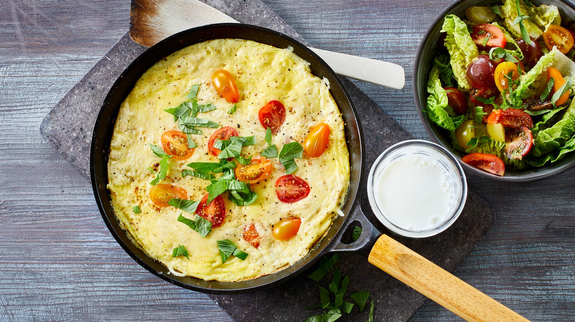 Omelett med tomat, ost og basilikum, med et glass melk og salat til