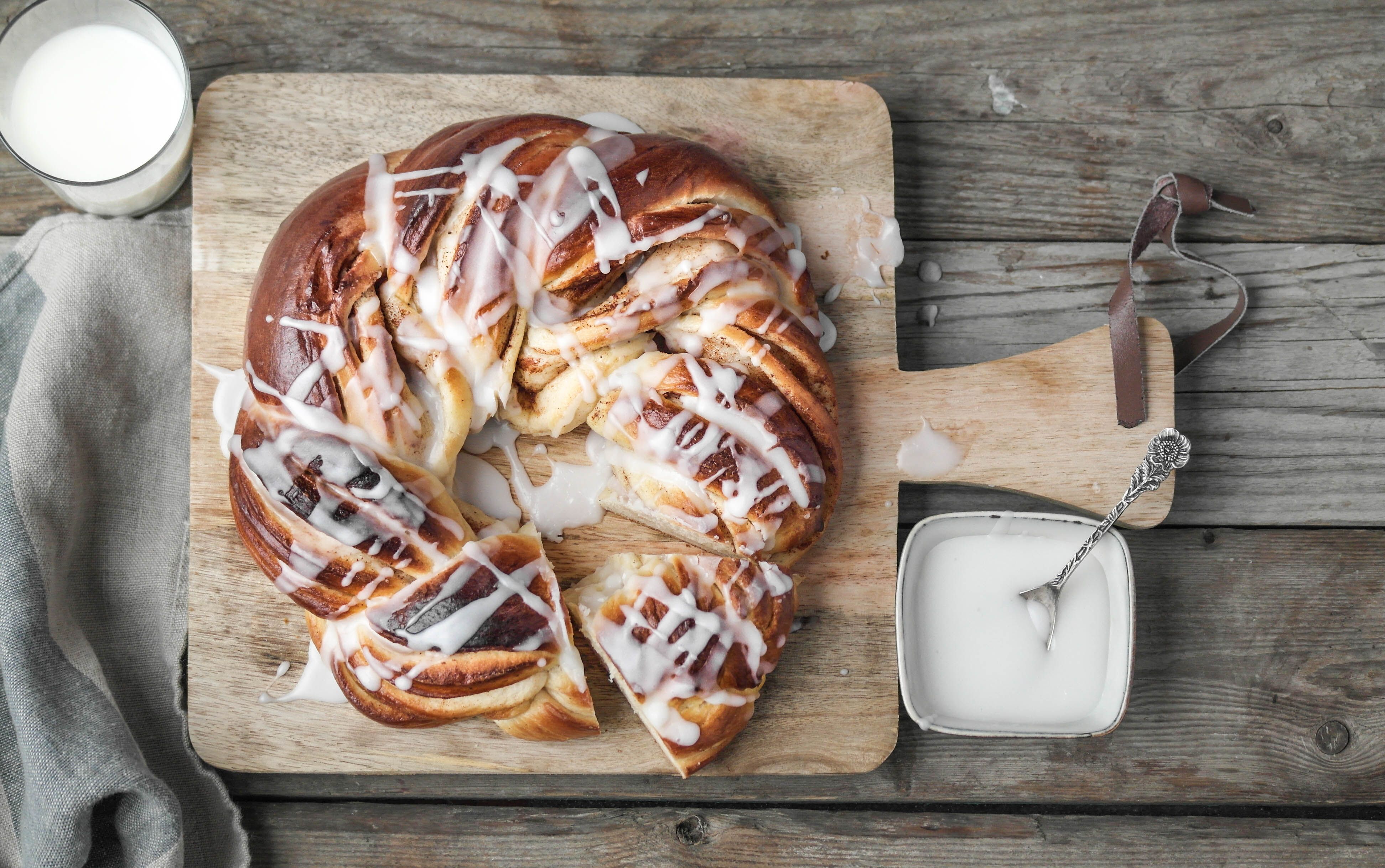 Kringle med melisglasur på fjøl med et glass melk ved siden