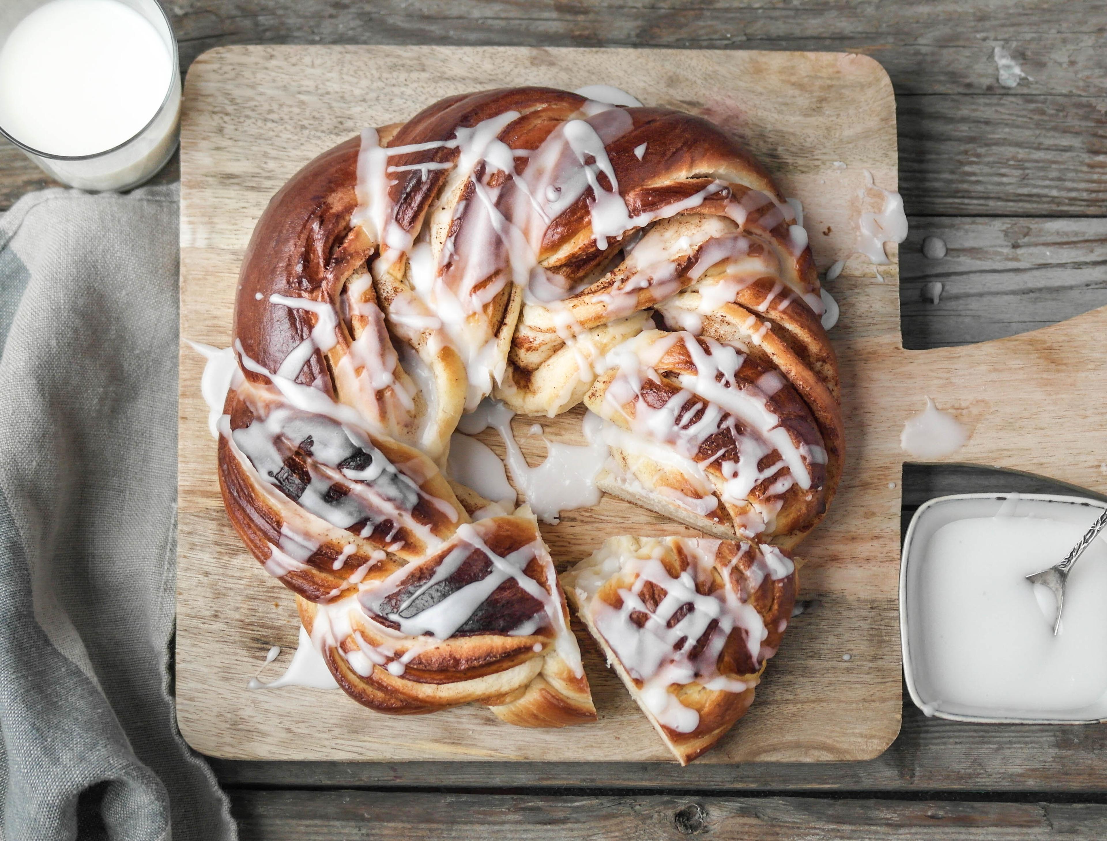 Kringle med melisglasur på fjøl med et glass melk ved siden