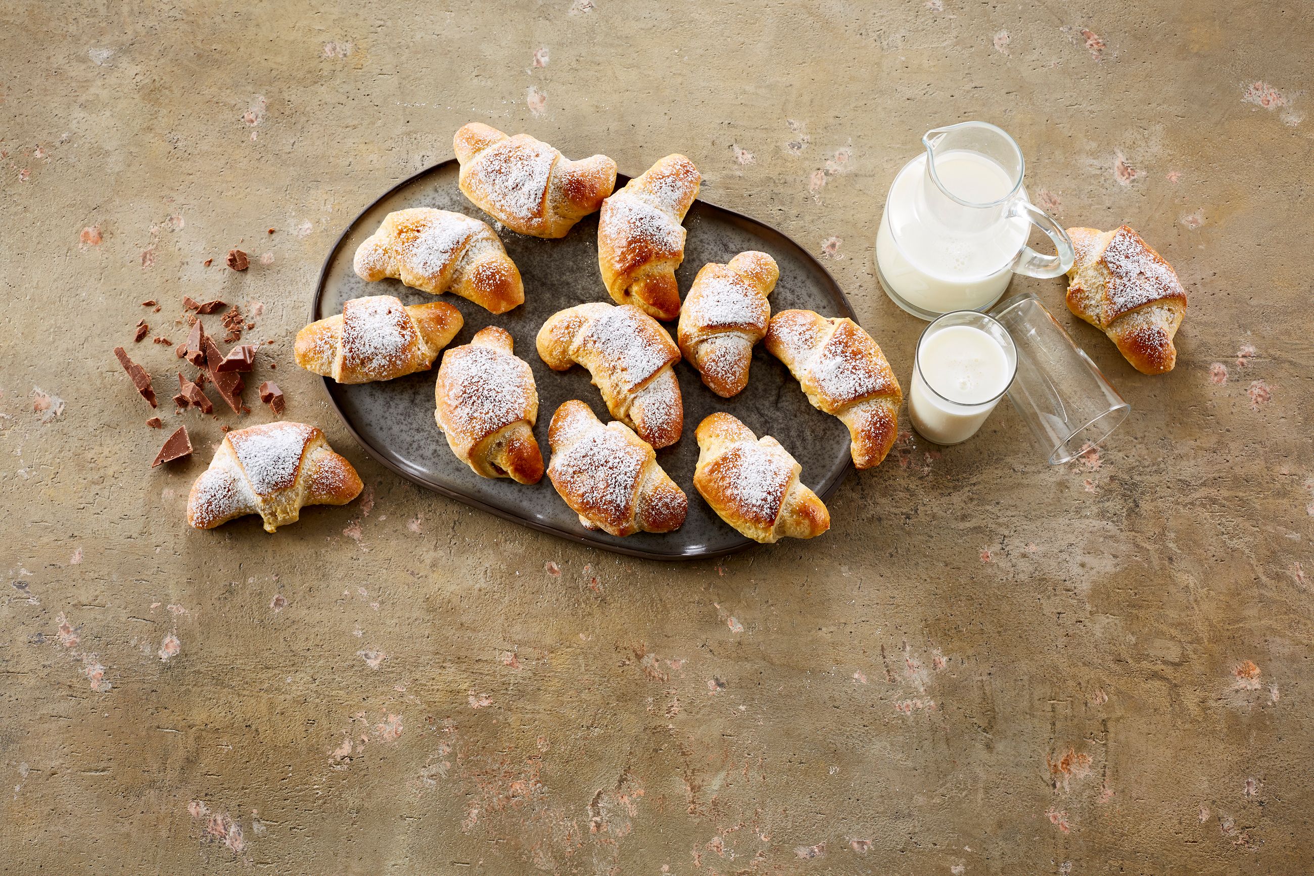Sjokoladehorn på et fat ved siden av en mugge og et glass med melk