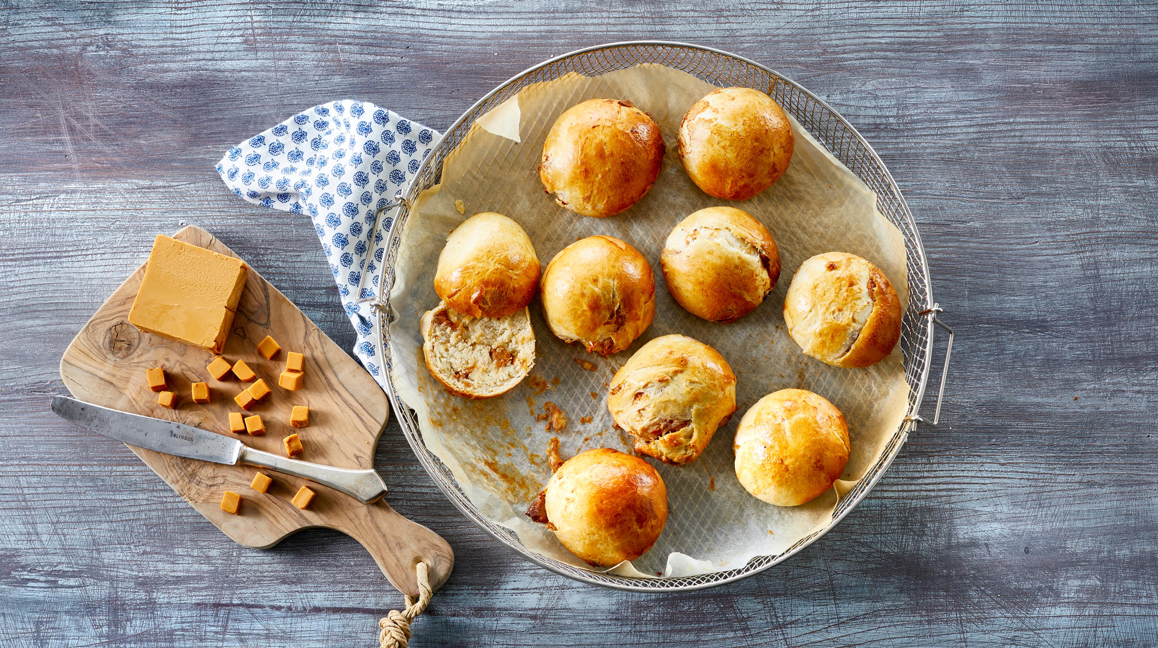 Brunostboller et på fat ved siden av brunost i terninger på en fjøl