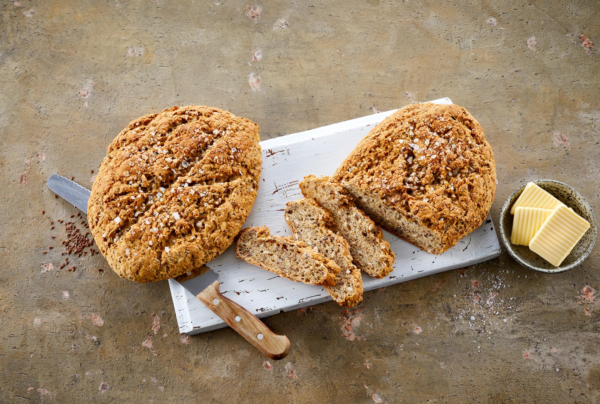 To runde brød med syrnet melk på en fjøl ved siden av en skål med smør i skiver.