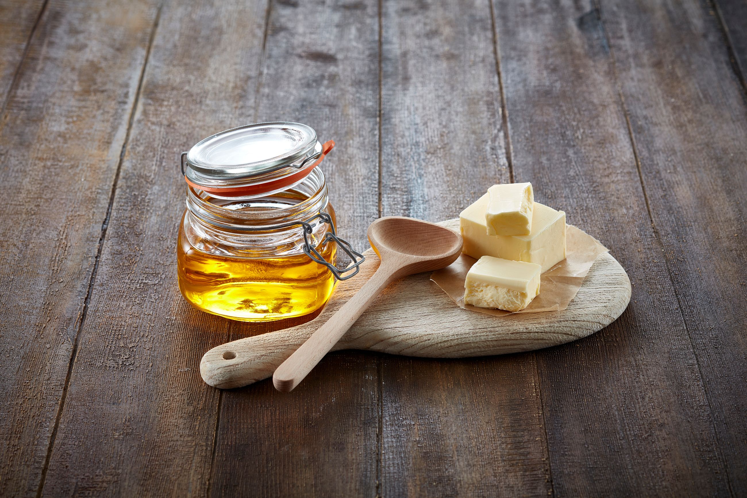 Krukke med ghee og noen smørklatter ved siden av