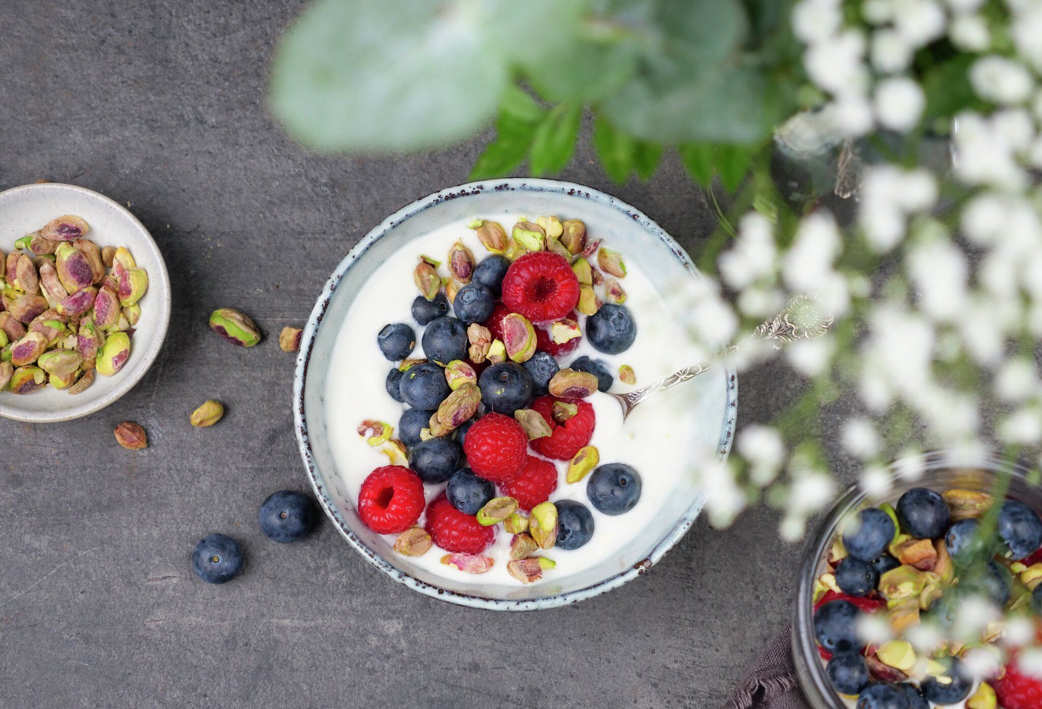 En skål med yoghurt toppet med blåbær, bringebær og pistasjenøtter