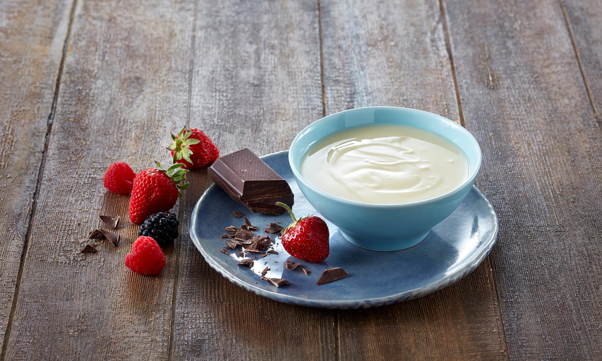 Søtet kondensert melk i en skål med jordbær rundt