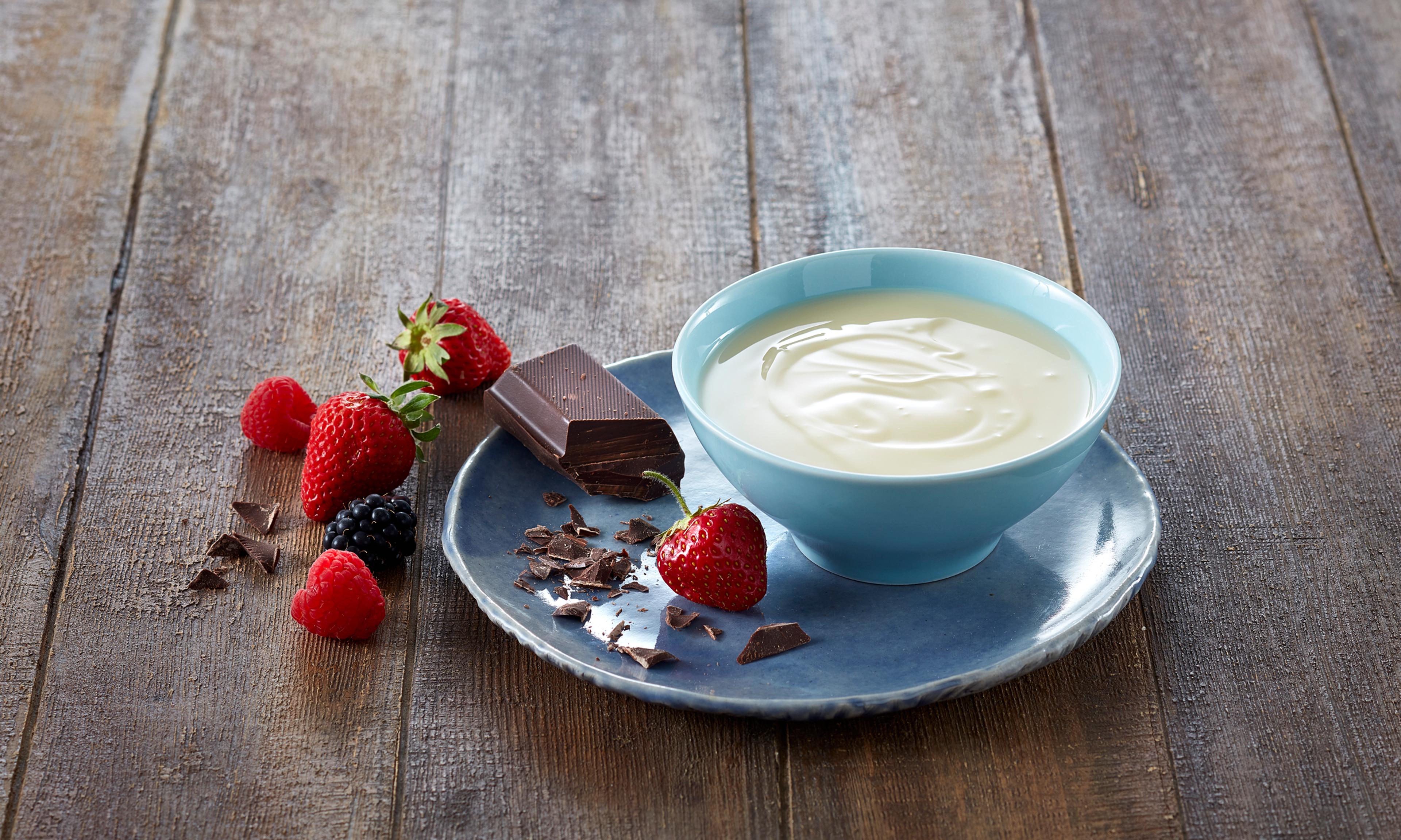 Søtet kondensert melk i en skål med jordbær rundt