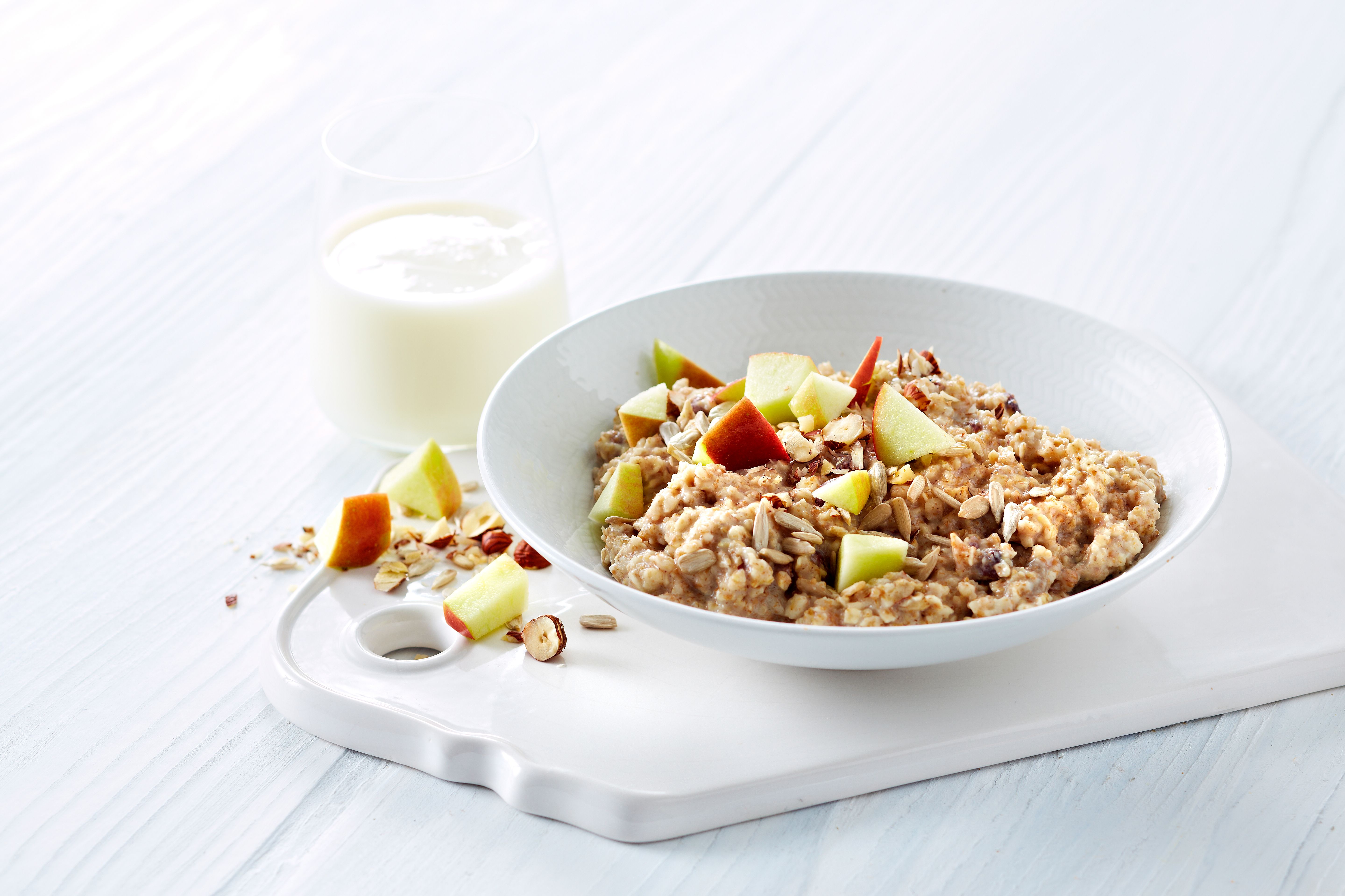 Hvetegrøt med eple, nøtter og kanel ved siden av et glass melk