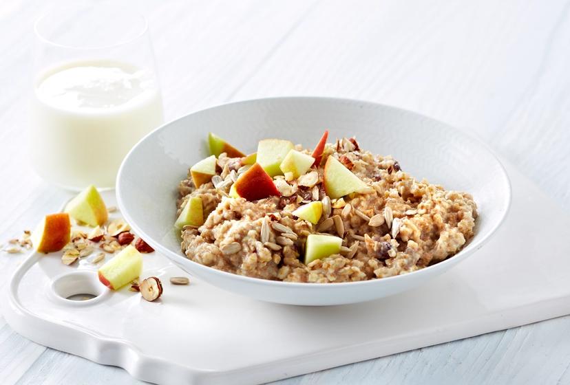 Hvetegrøt med eple, nøtter og kanel ved siden av et glass melk