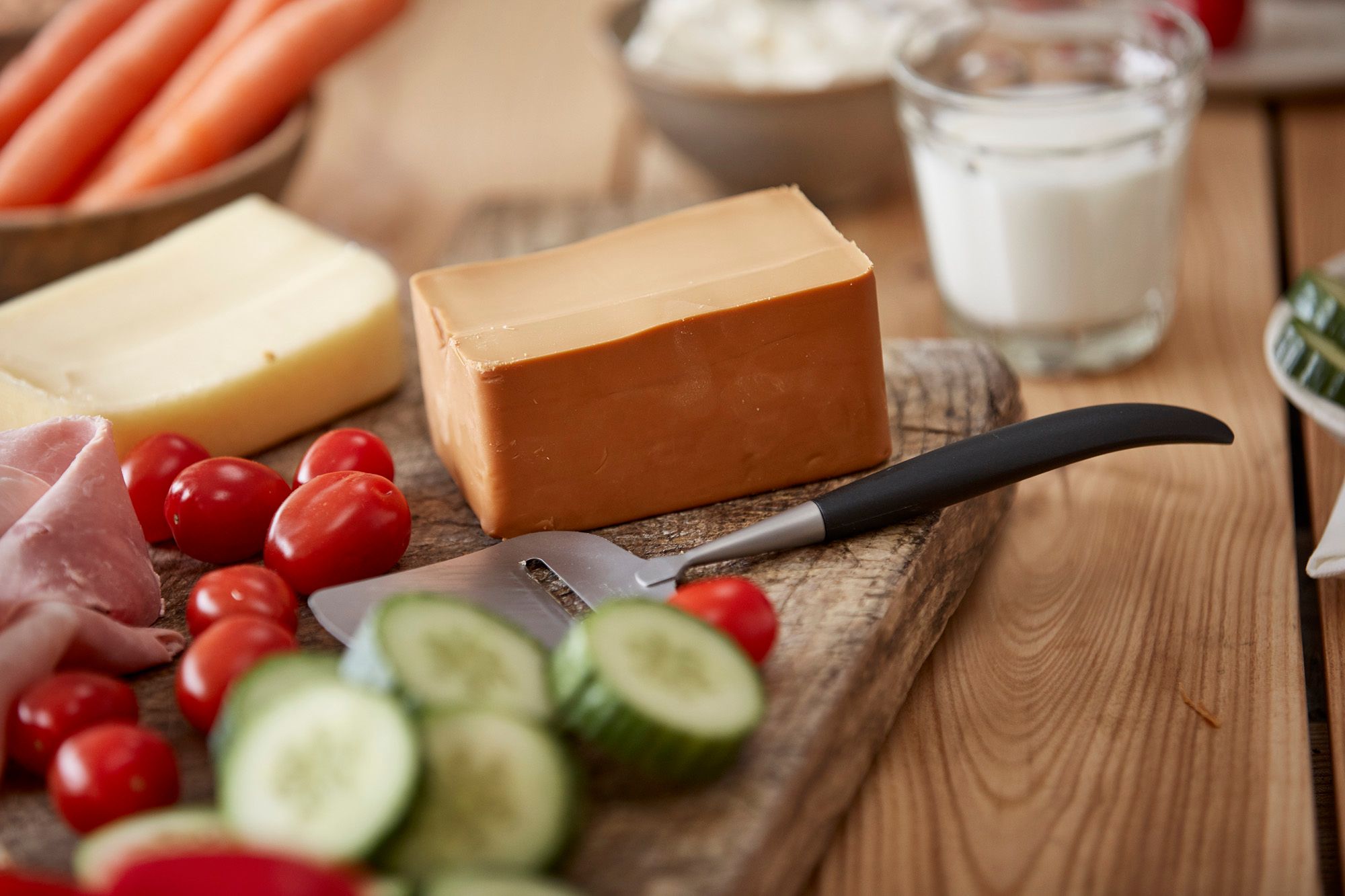 kjøkkenbenk med gulost, brunost og ett glass melk, ostehøvvel 