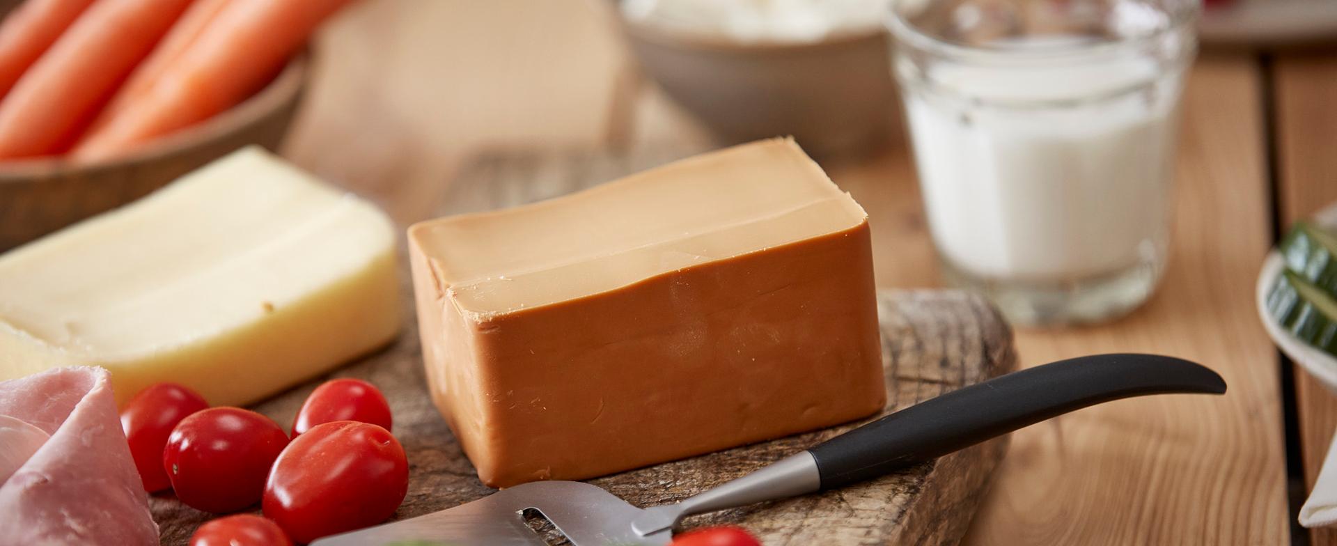 kjøkkenbenk med gulost, brunost og ett glass melk, ostehøvvel