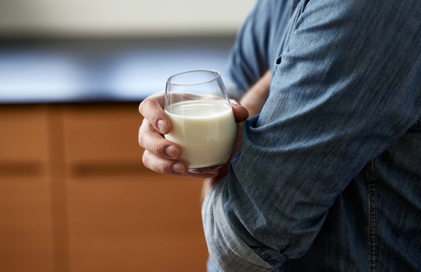 a man is holding a glass of milk in his hand .