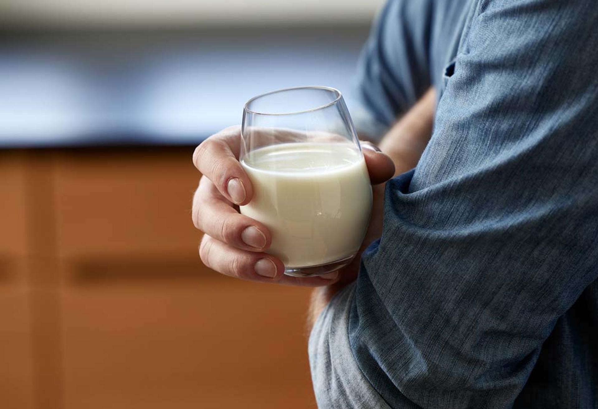 a man is holding a glass of milk in his hand .