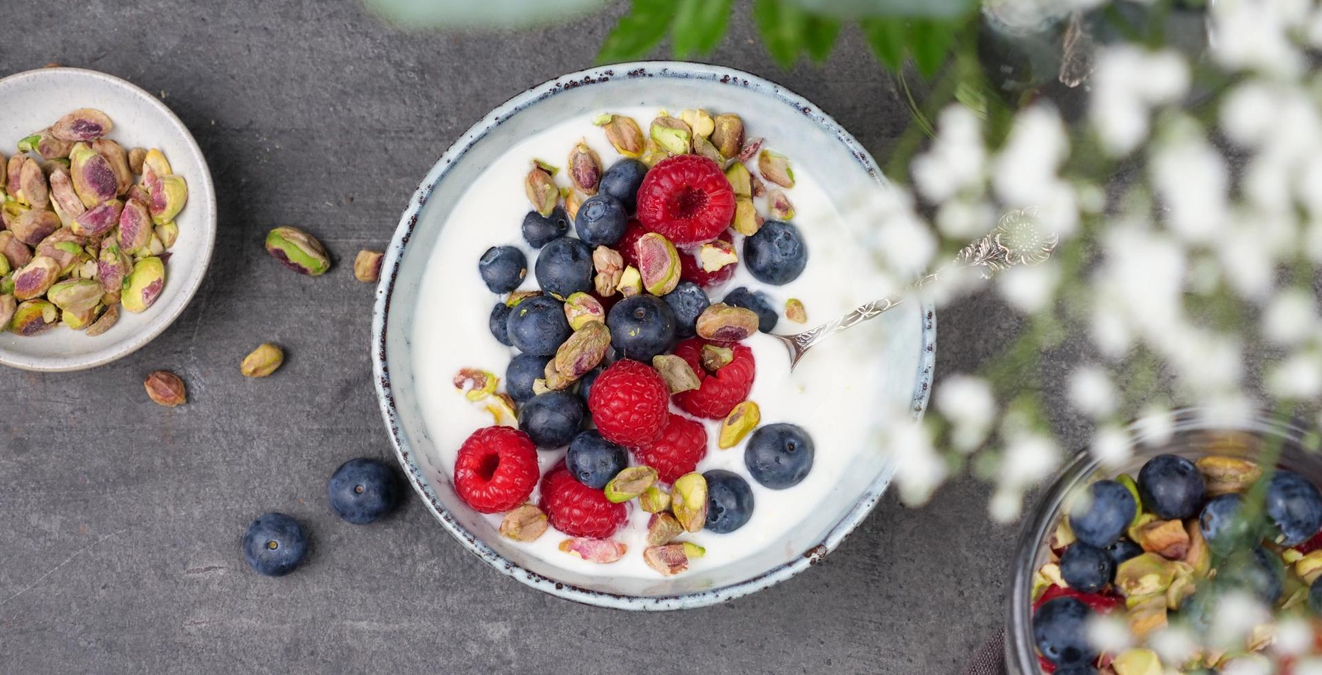 Skål med yoghurt, med bringebær, blåbær og pistasjenøtter