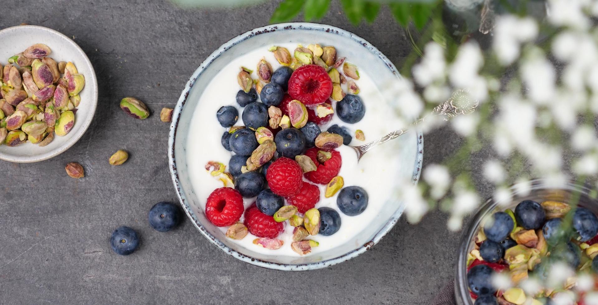 Skål med yoghurt, med bringebær, blåbær og pistasjenøtter