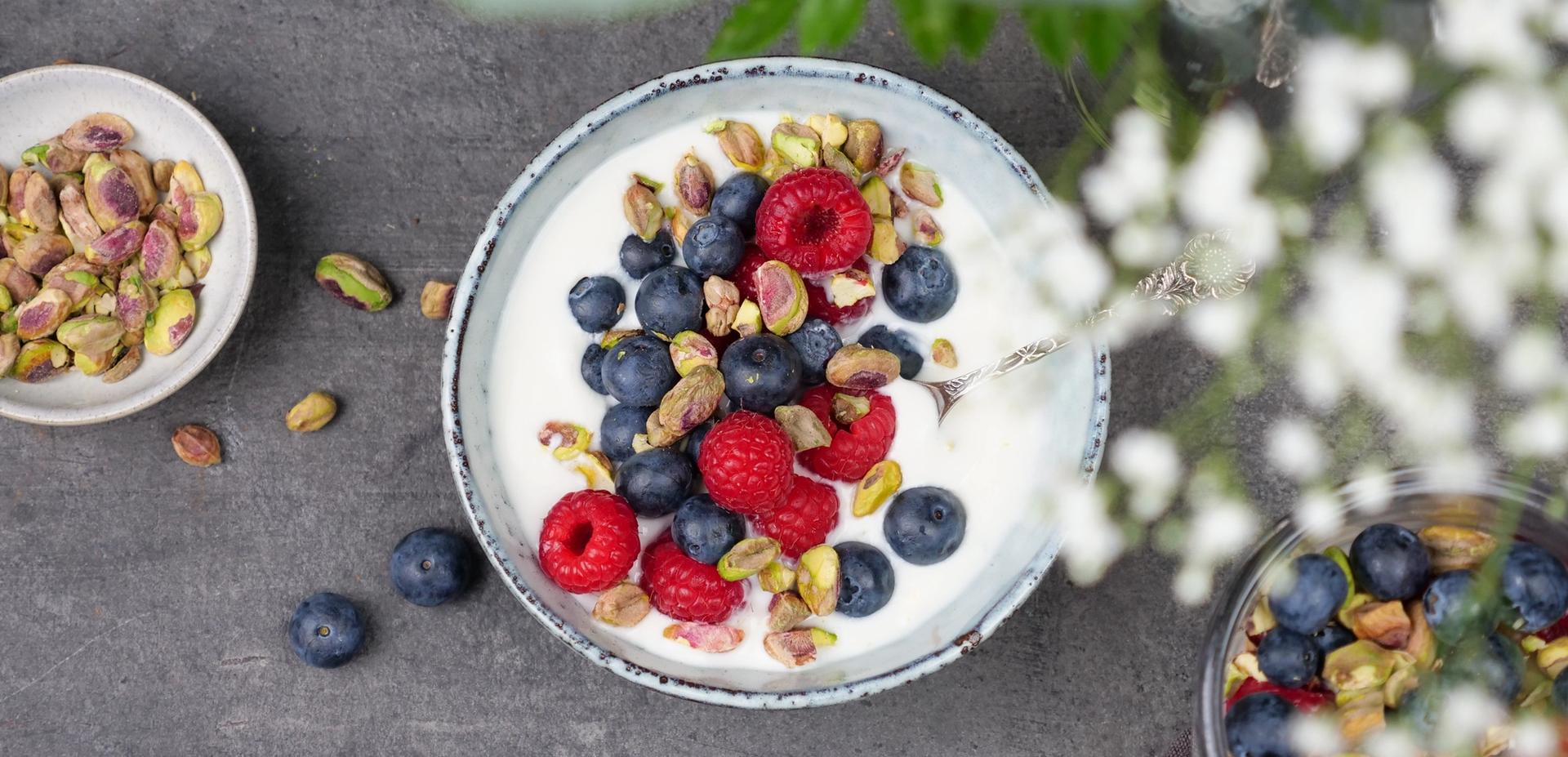 Skål med yoghurt, med bringebær, blåbær og pistasjenøtter